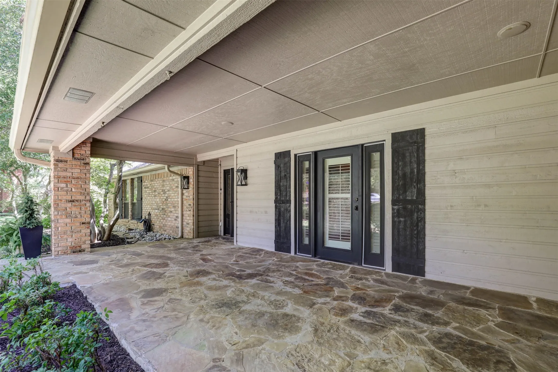 Inviting stone-floored entry porch leading to the custom front door.