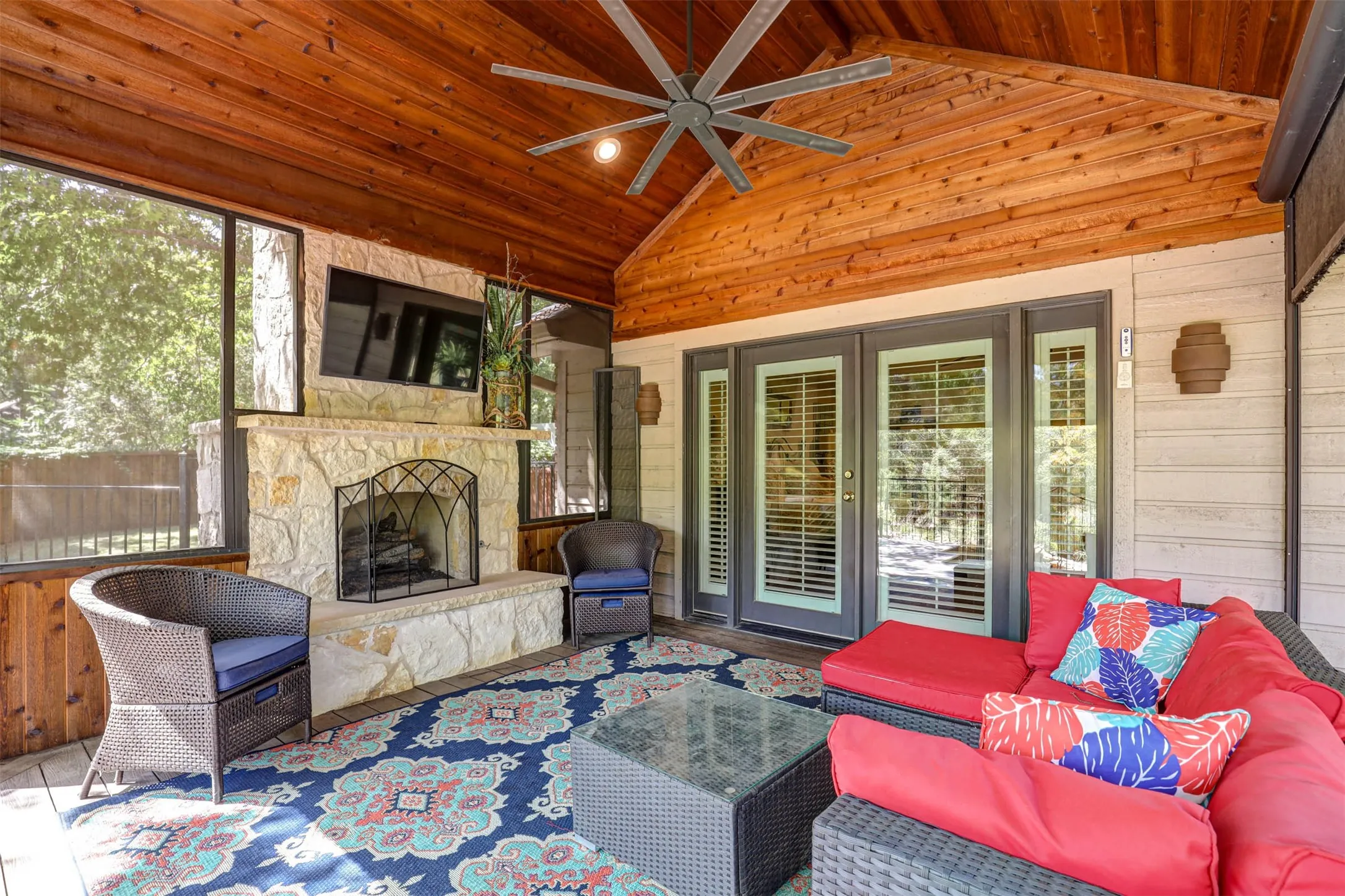Expansive covered lanai with stone fireplace, vaulted ceiling, remote control screens, and access to the primary suite.