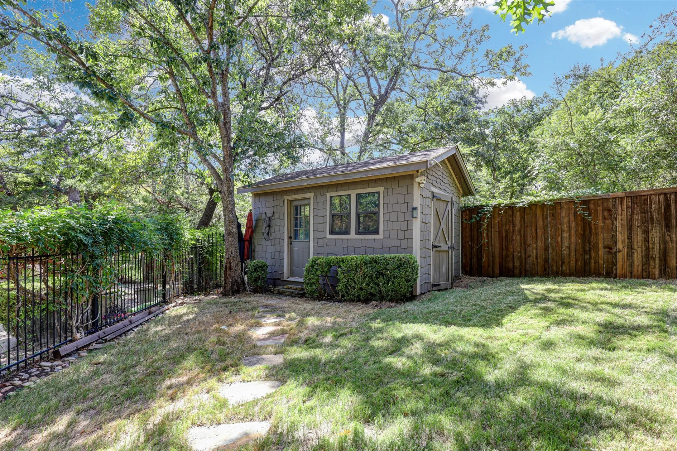 
Well kept backyard shed with stone paver walkway and shaded landscaping.
