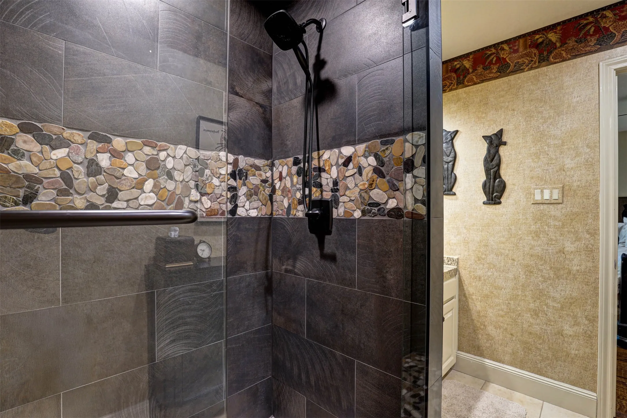 Oversized walk in shower with pebble mosaic detail and clean, modern tilework.