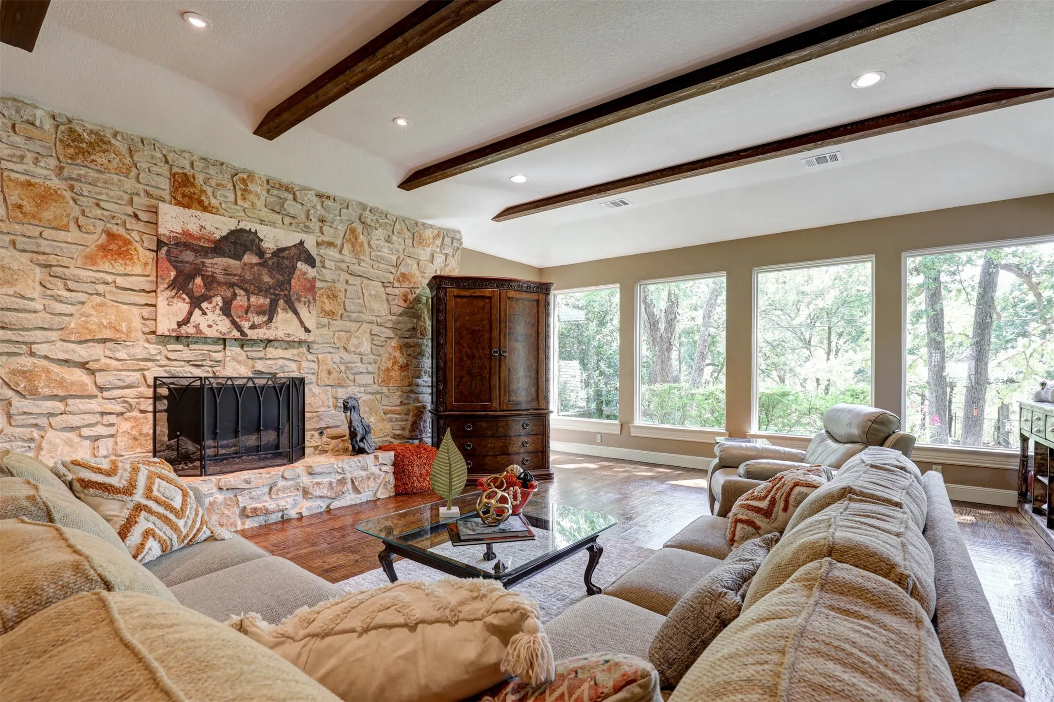 Bright living area with a full wall of windows and a striking stone fireplace.