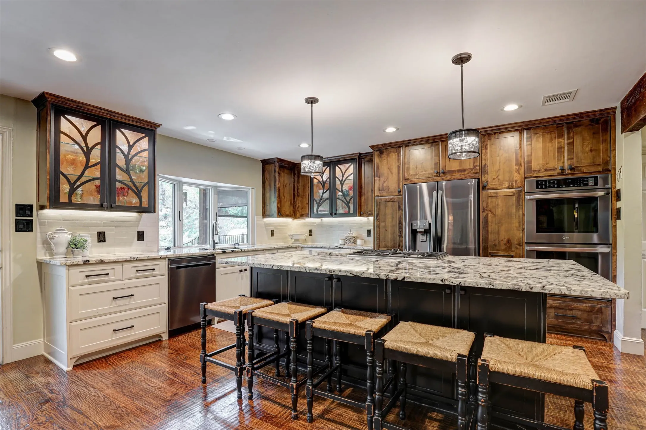 Beautifully appointed kitchen with large island, breakfast bar seating, and custom glass cabinetry.