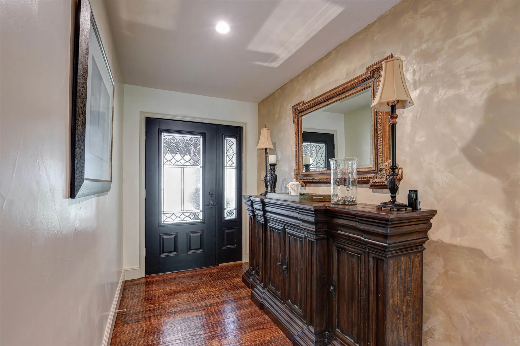 Elegant entryway with rich wood floors and an accent wall.