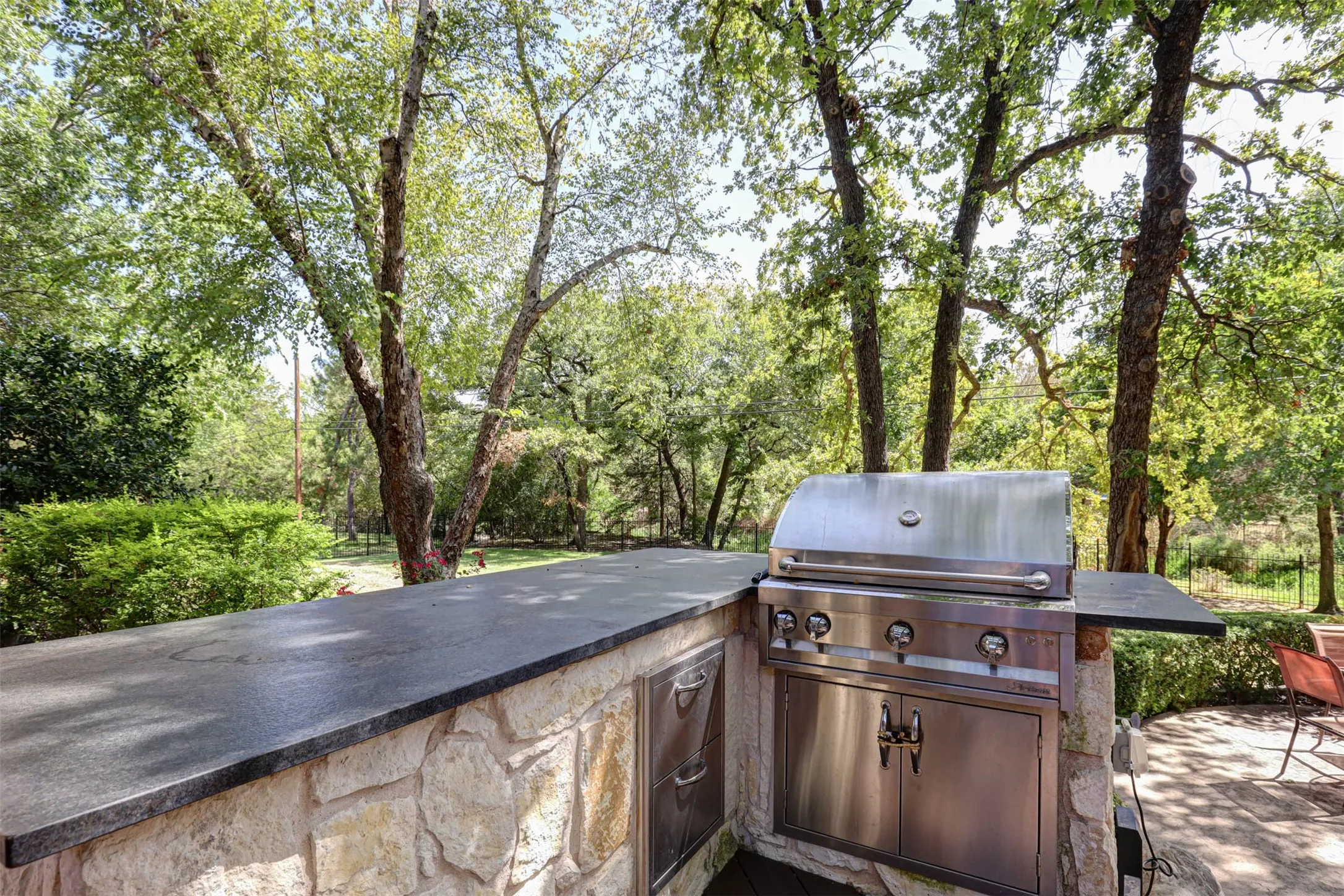 Built in outdoor grill with stone surround and ample counter space for cooking and gathering.