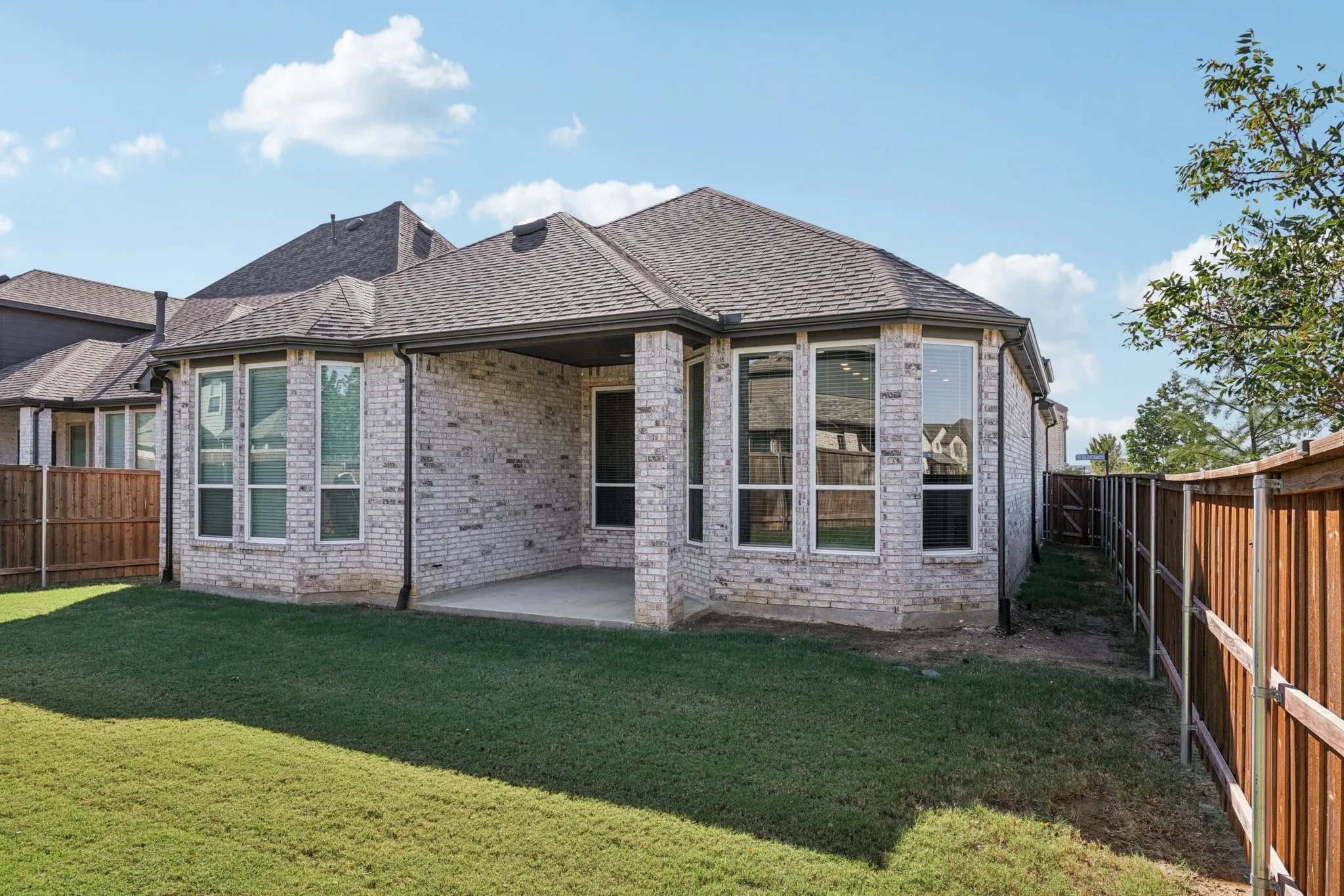 Exterior featuring a covered patio, brick facade, and fenced yard