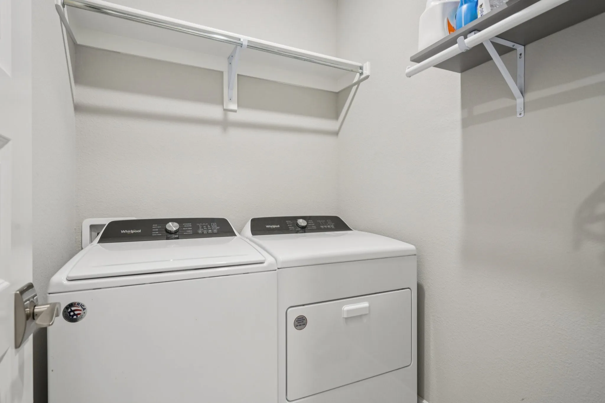 Integrated laundry area with white appliances and built-in shelving