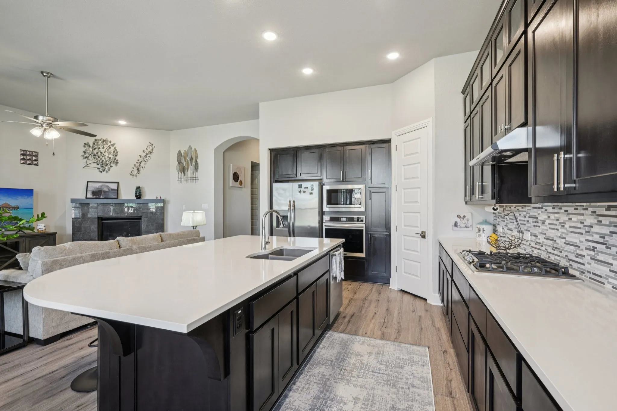 Kitchen featuring dark wood-finish cabinetry, light-toned countertops, and a mosaic tile backsplash