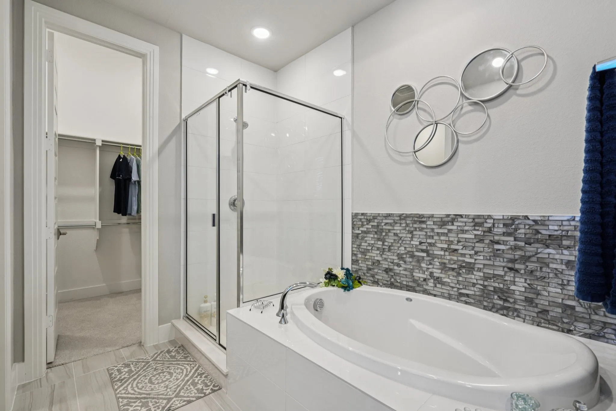 Walk-in shower with glass enclosure, separate soaking tub, and mosaic tile accent wall