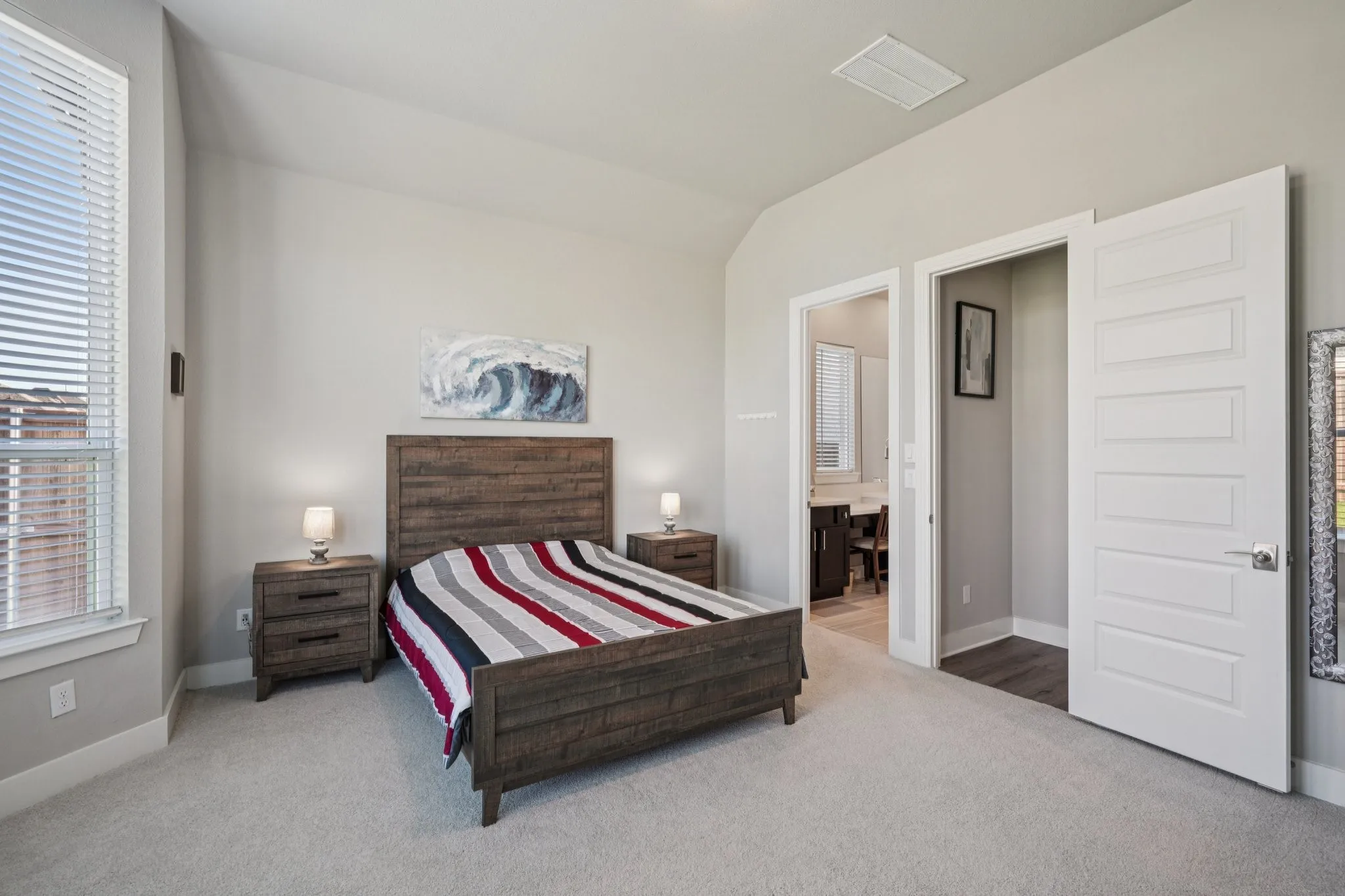 Carpeted bedroom featuring a large window, vaulted ceiling, and white trim