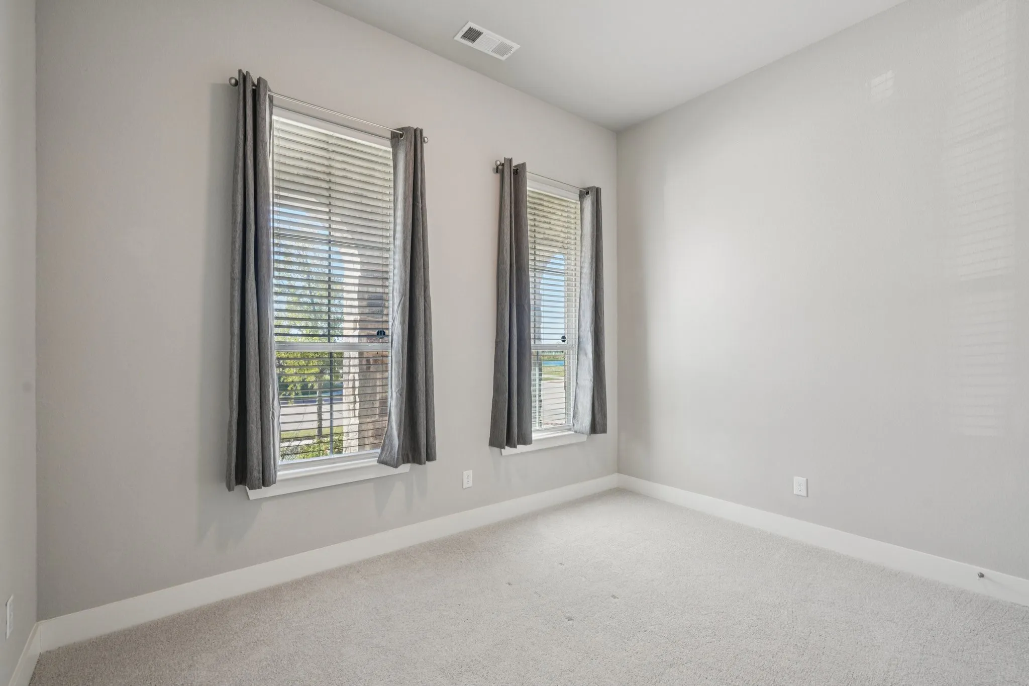 Plush carpeting, light gray wall finishes, white trim, and two windows with blinds