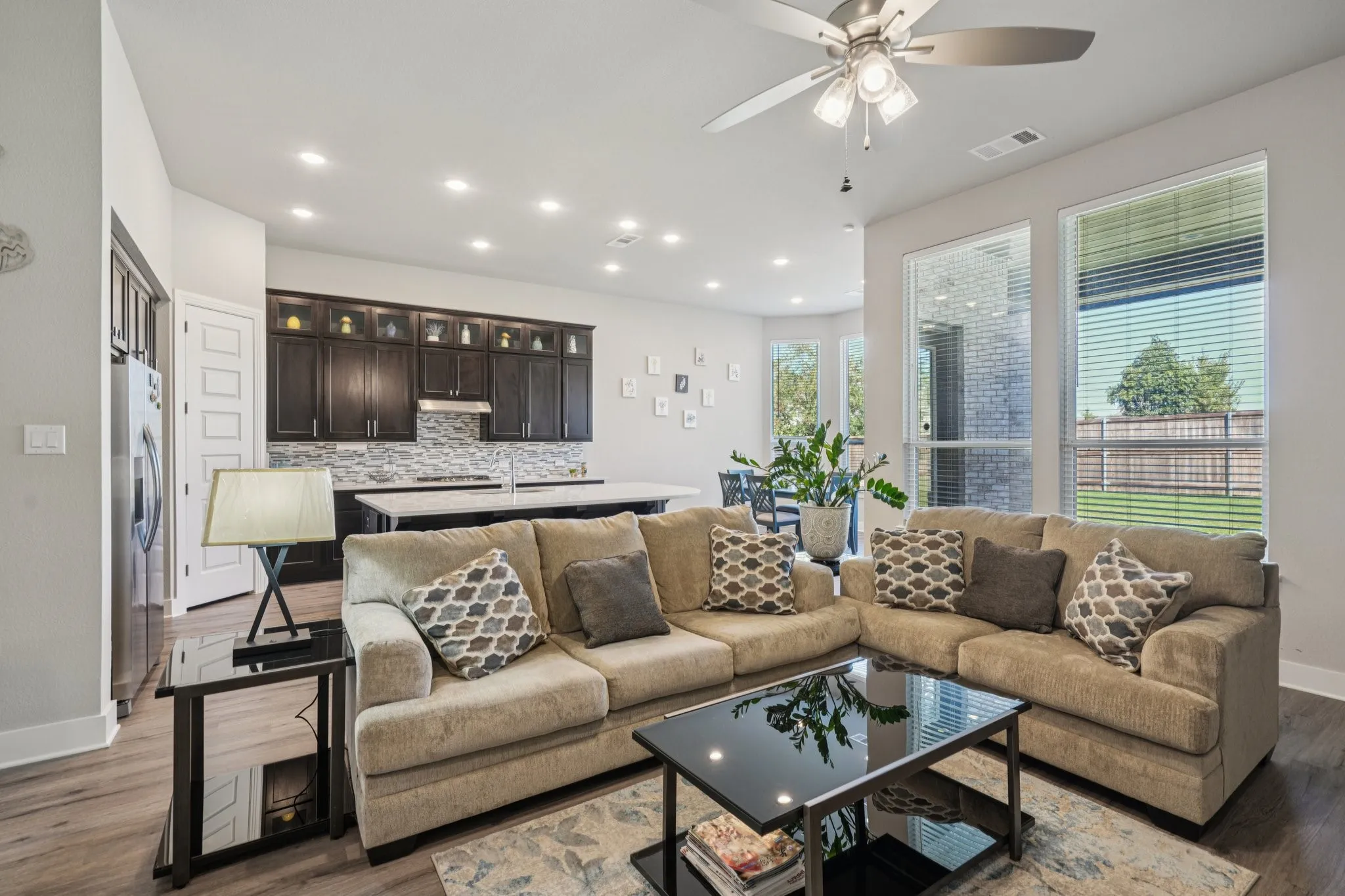 Open-concept living space with wood-finish flooring, recessed lighting, ceiling fan, and large windows