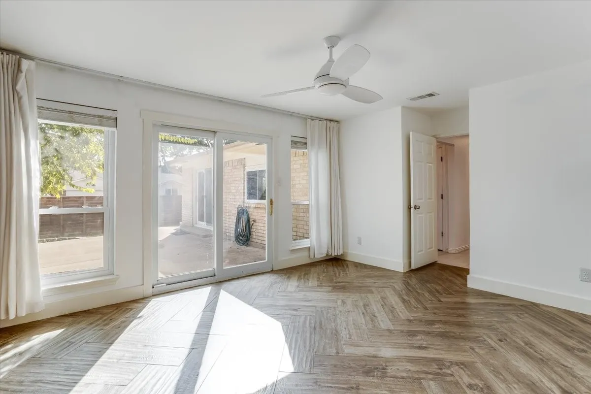 Wood-finish flooring in a herringbone pattern, white walls, and a ceiling fan