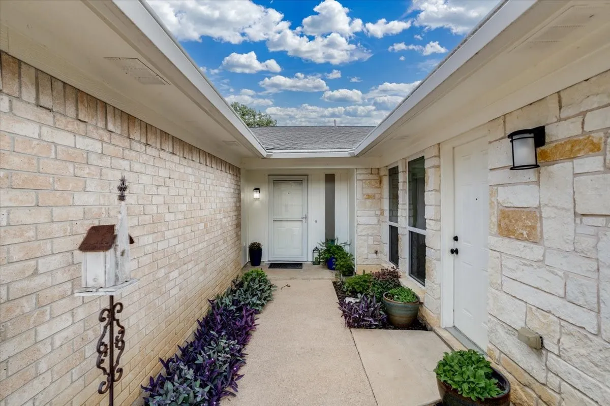 Covered entryway featuring light-toned brick and stone veneer