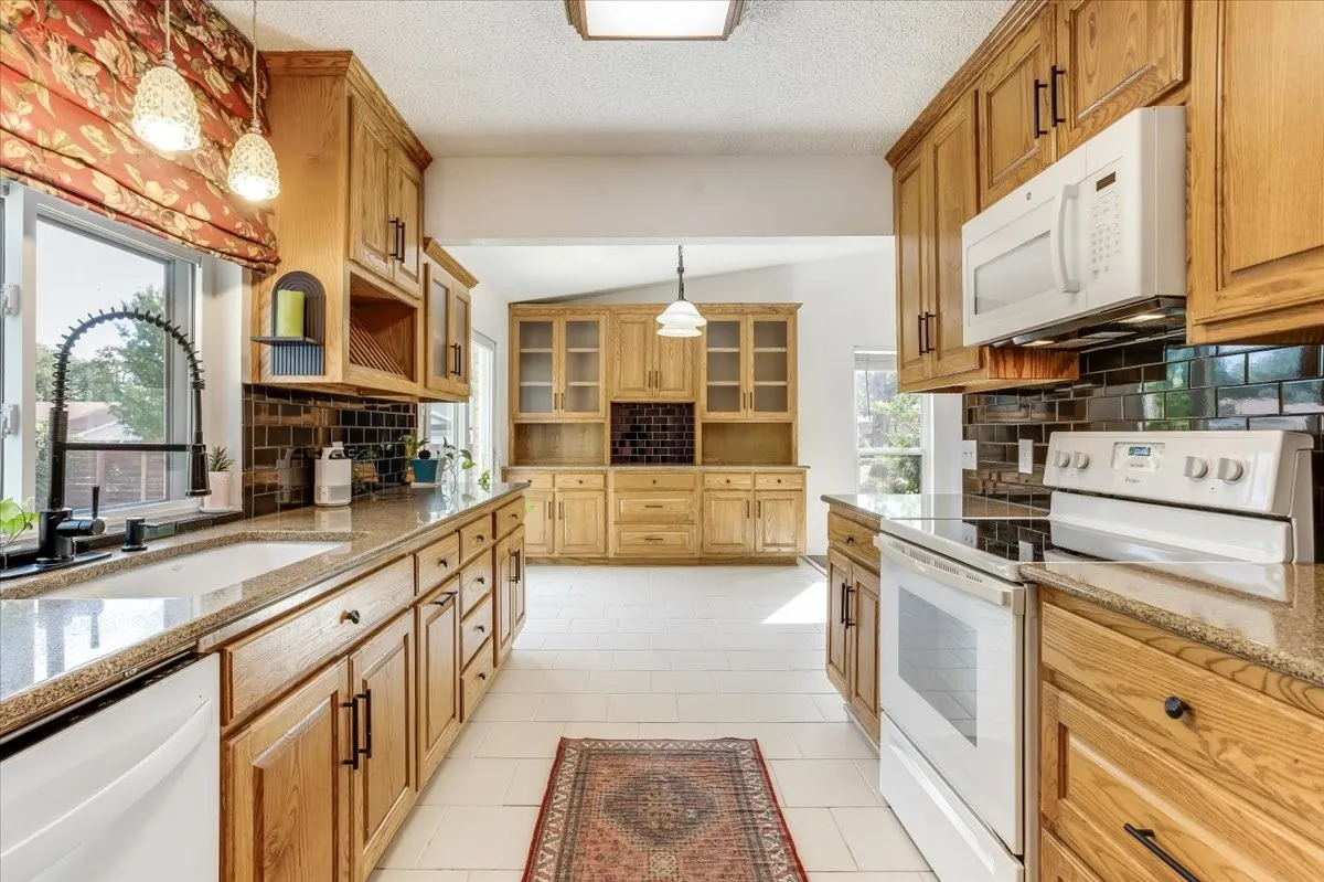 Kitchen featuring extensive wood cabinetry, stone-finish countertops, and a black subway tile backsplash