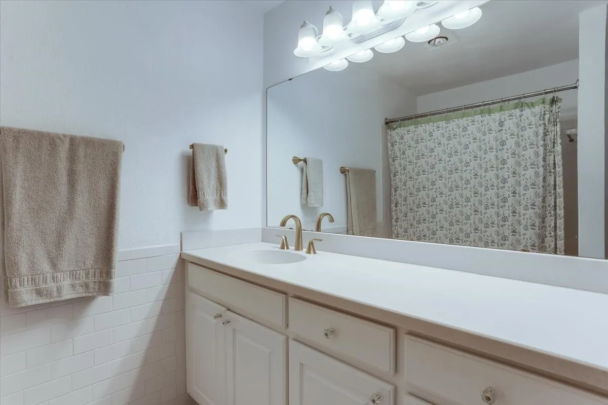 White vanity with integrated sink, gold-finish faucet, and crystal-style drawer pulls
