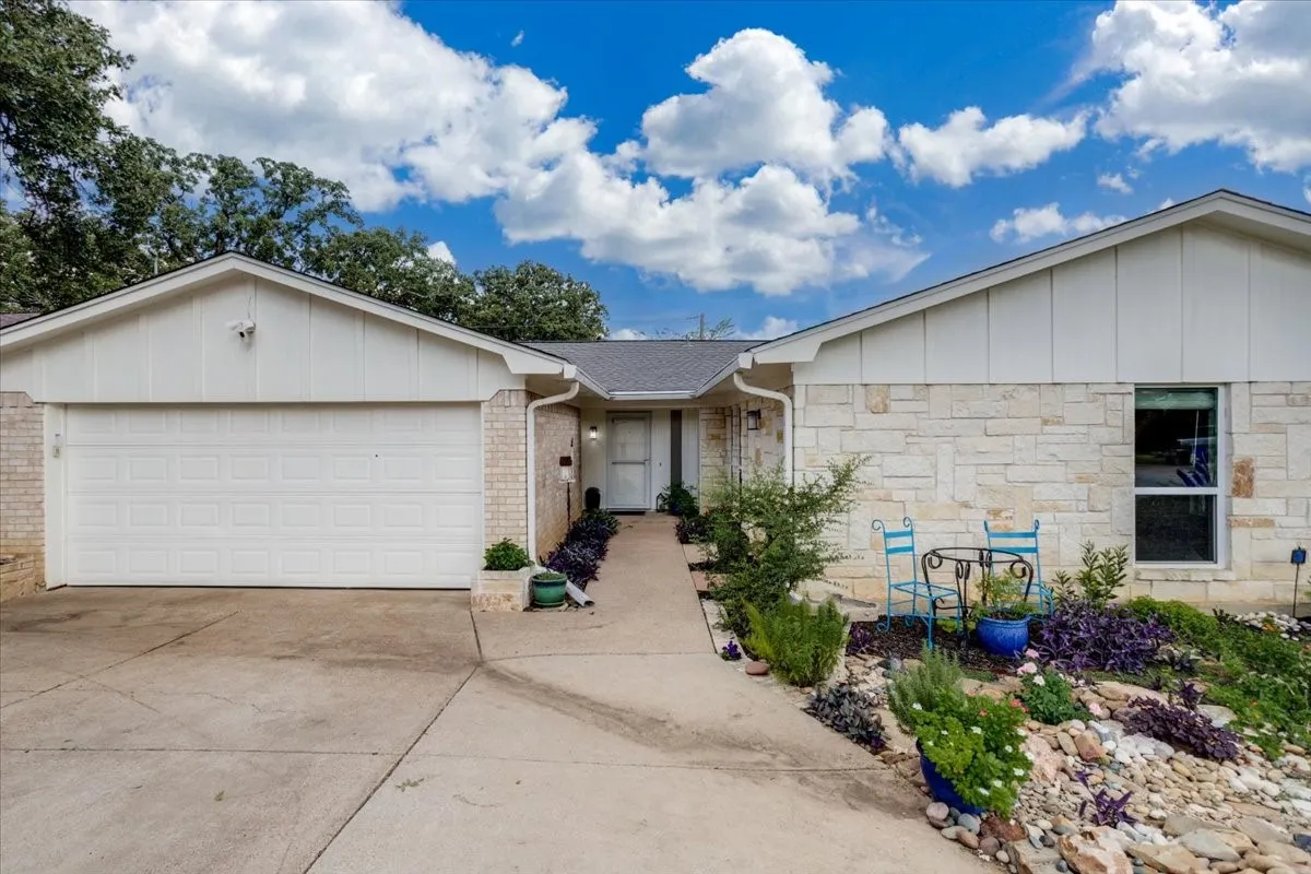 Exterior featuring a stone facade, white siding, and an attached garage