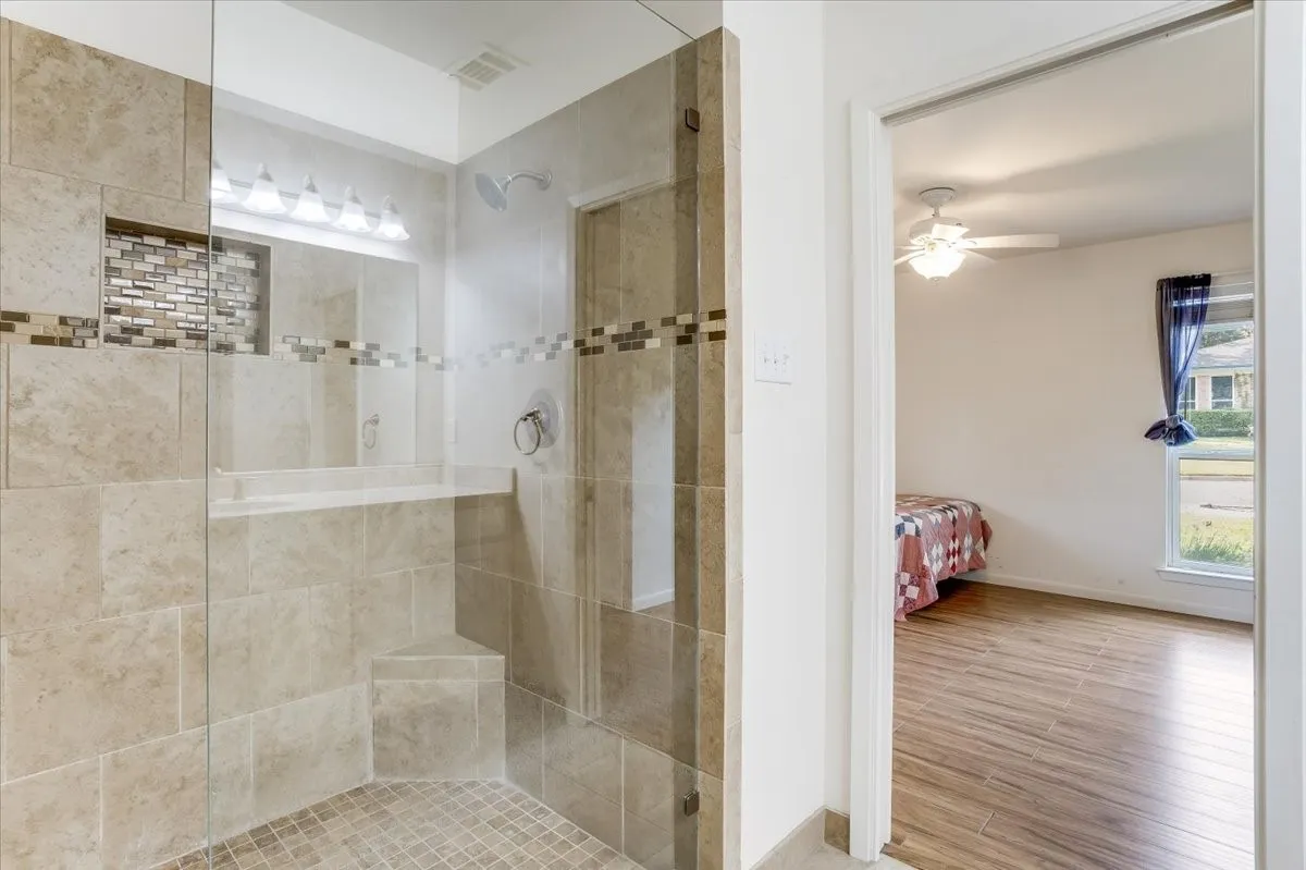 Glass-enclosed shower with large format tile, mosaic tile accent, and built-in shower bench