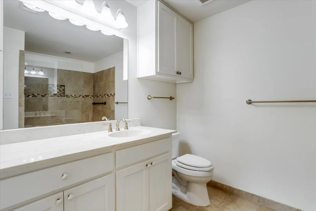 White vanity with an integrated sink, polished chrome faucet, and overhead cabinet storage