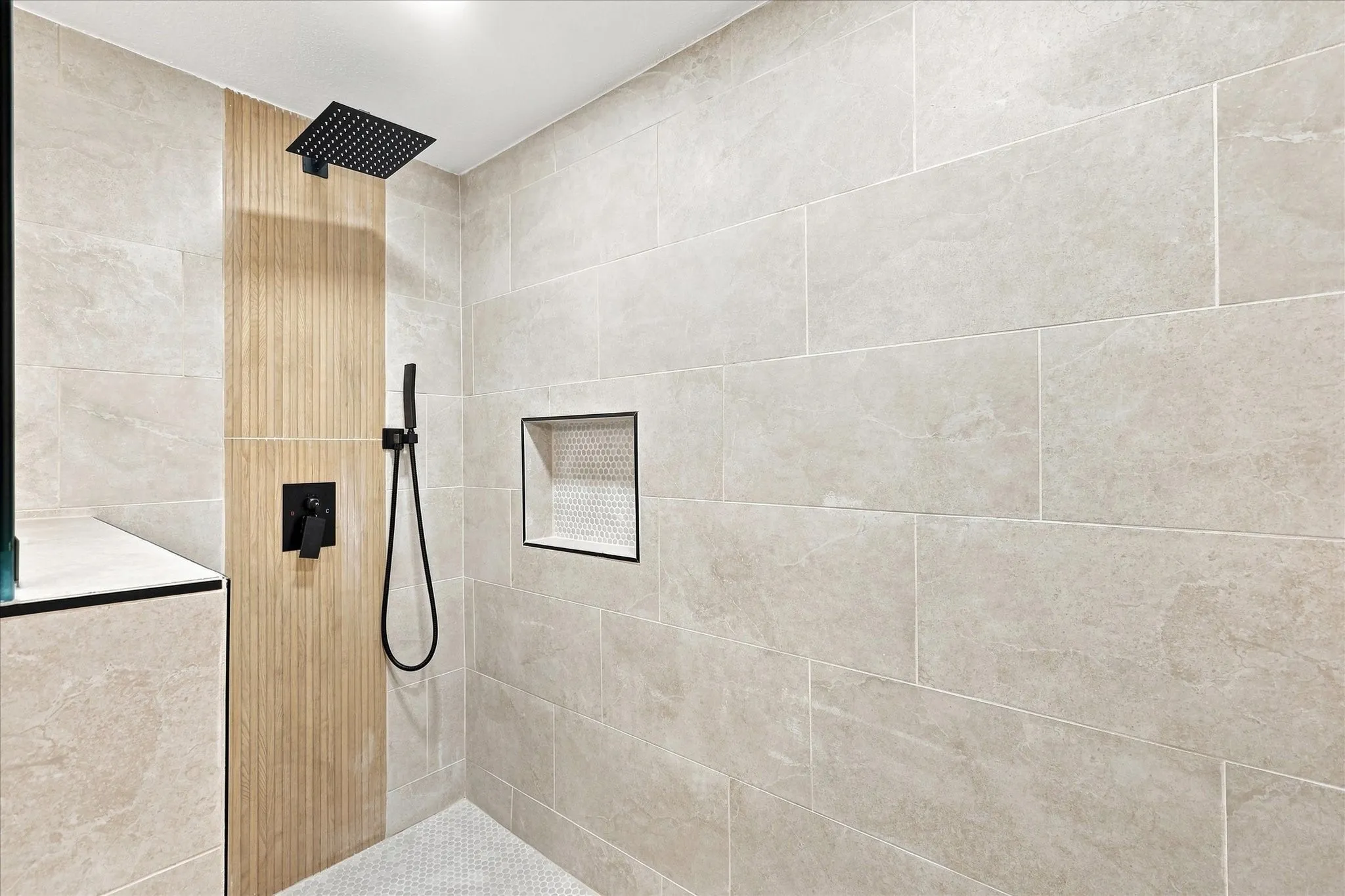 Shower featuring a rain showerhead, handheld sprayer, textured wood-finish accent wall, and built-in recessed niche