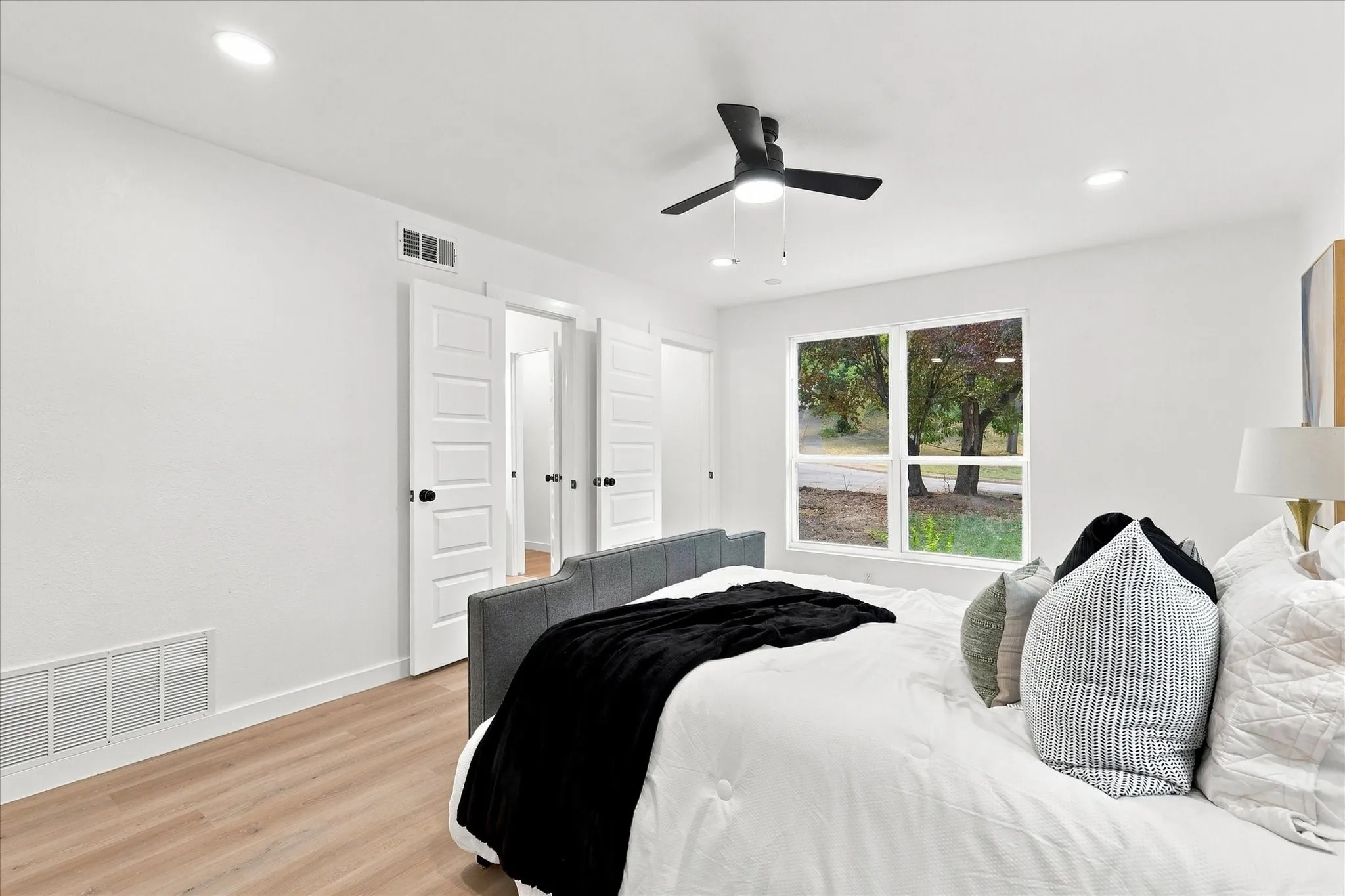 Recessed lighting, wood-finish flooring, ceiling fan, white walls, and a window with a natural backdrop