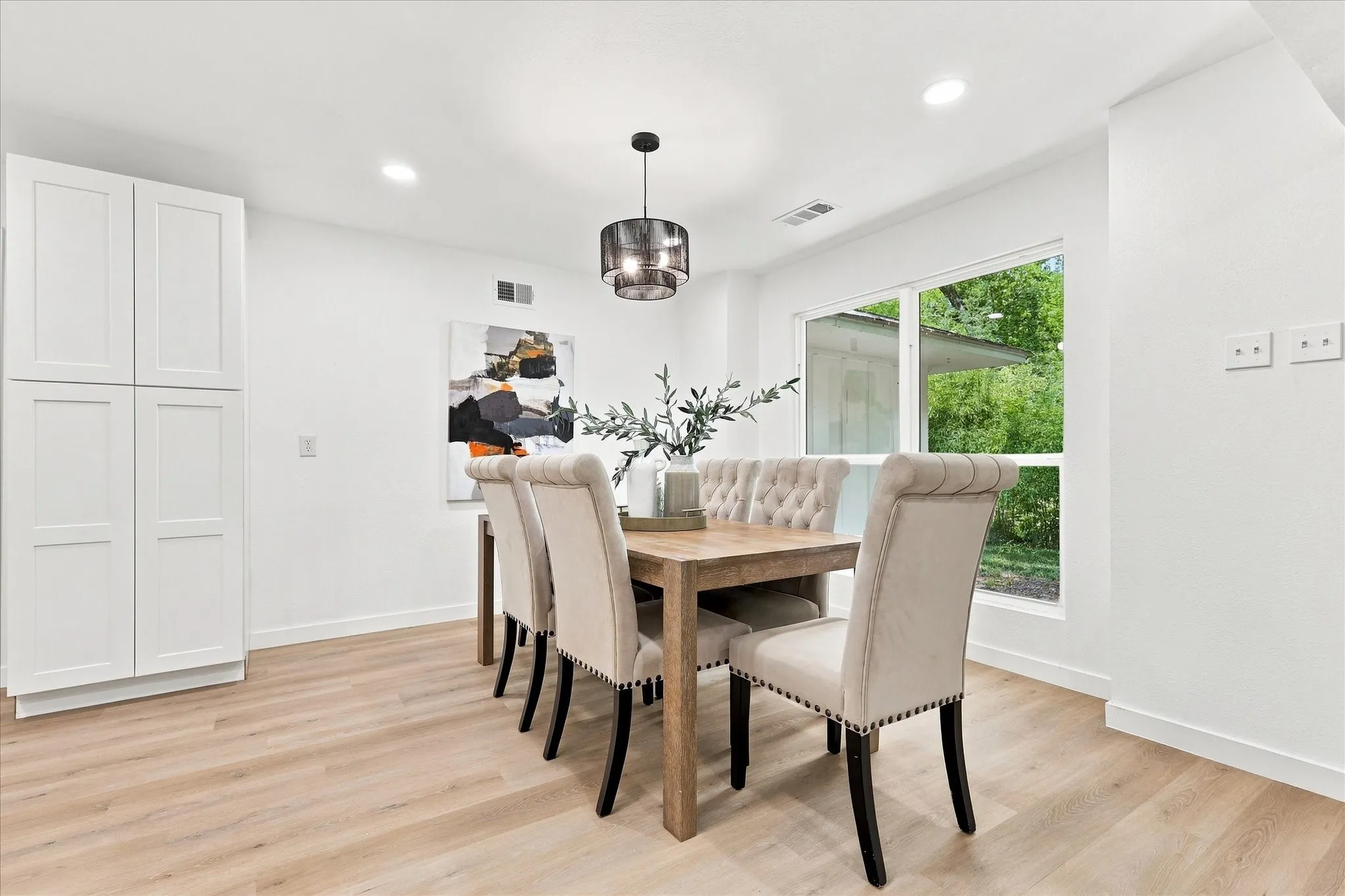 White shaker-style cabinetry, wood-finish flooring, a contemporary drum pendant light, and recessed ceiling lighting