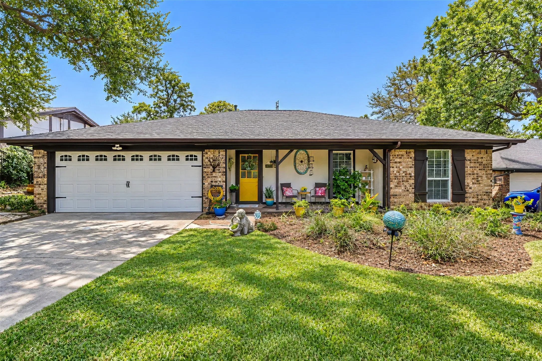 Brick exterior with dark shutters, covered front porch, and a two-car garage