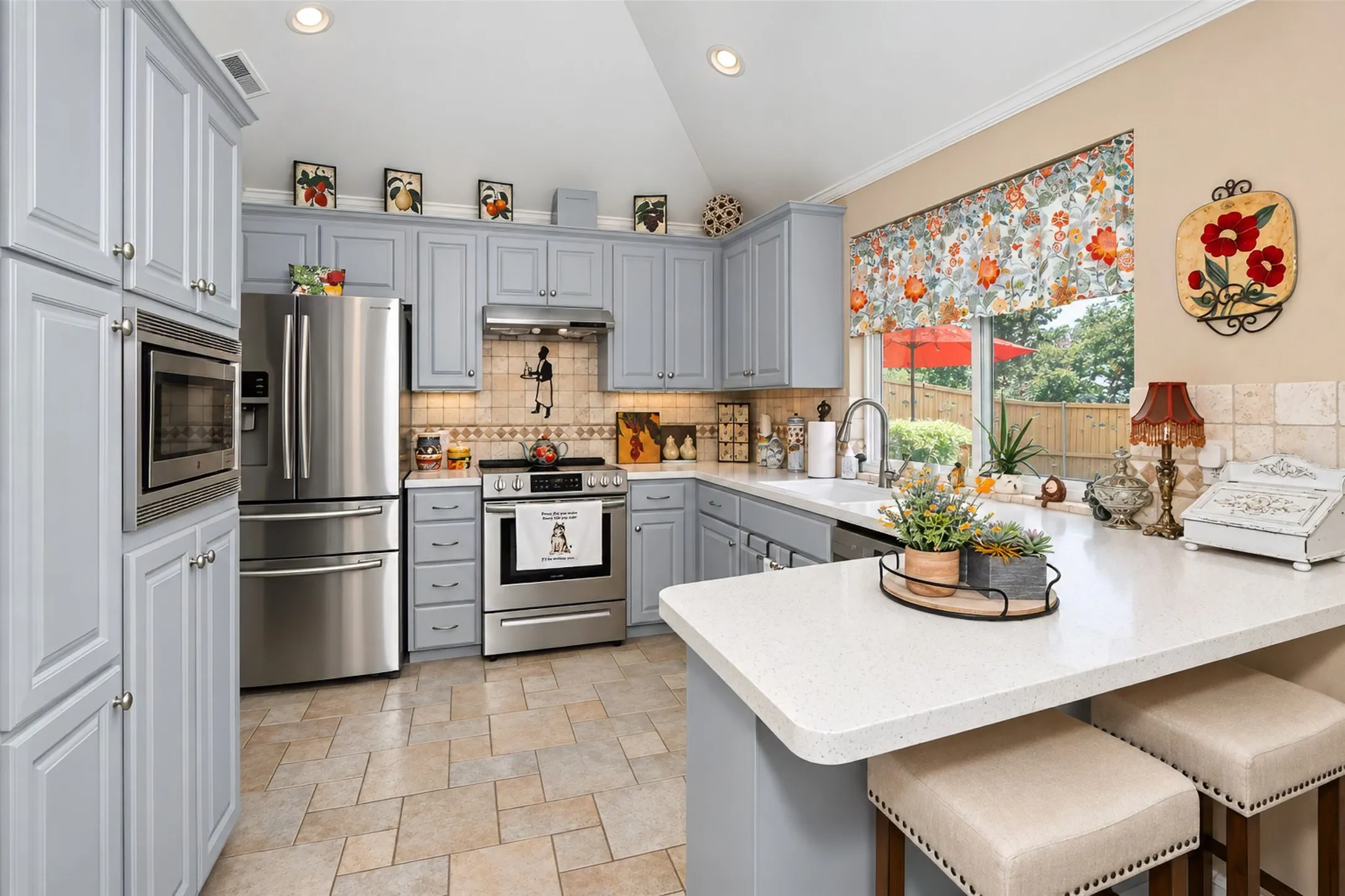 Kitchen featuring light gray cabinetry, stainless steel appliances, light-toned countertops, tile flooring, and a window above the sink