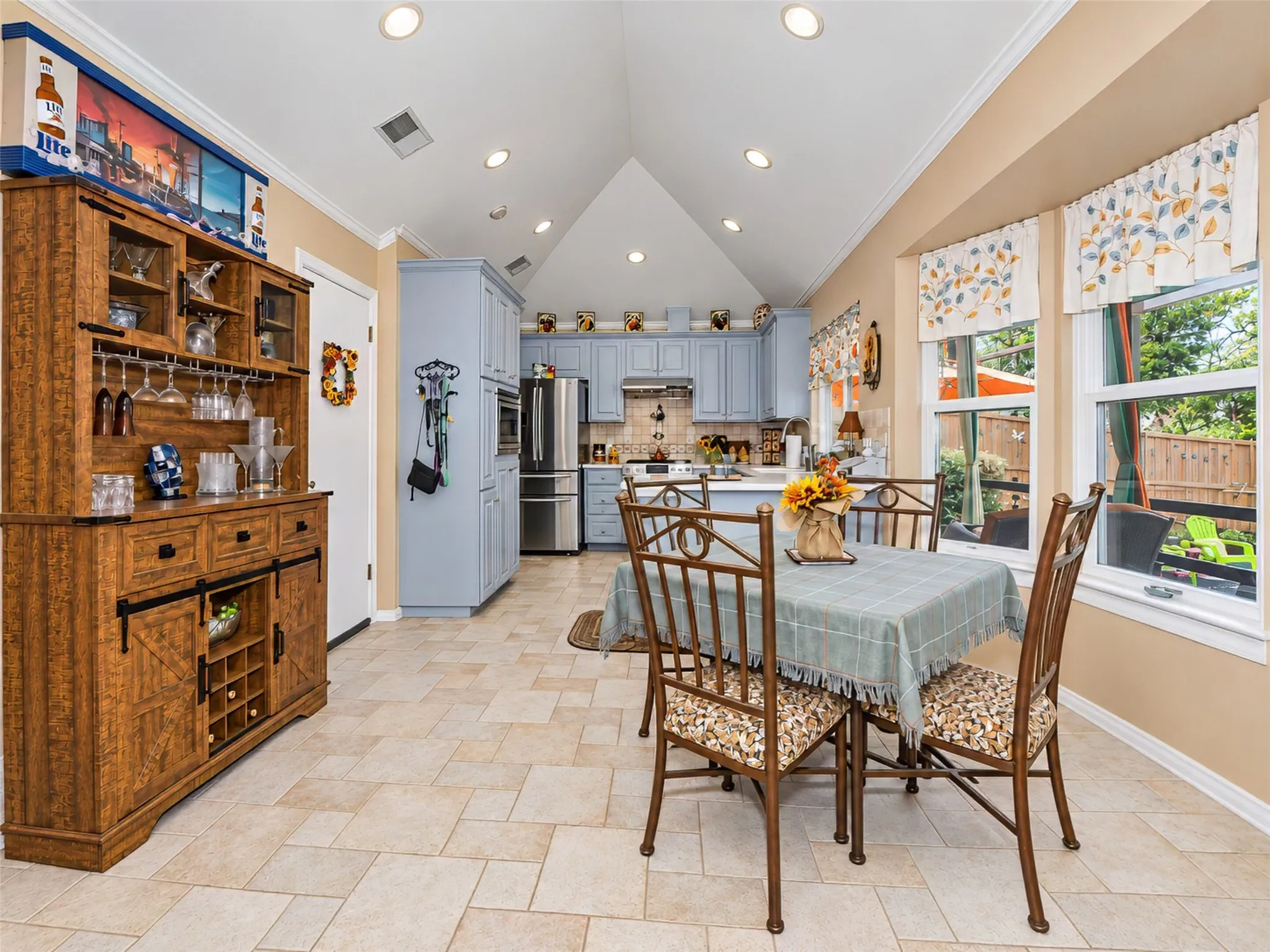 Vaulted ceiling with recessed lighting, kitchen featuring light blue cabinetry, stainless steel appliances, and a built-in oven