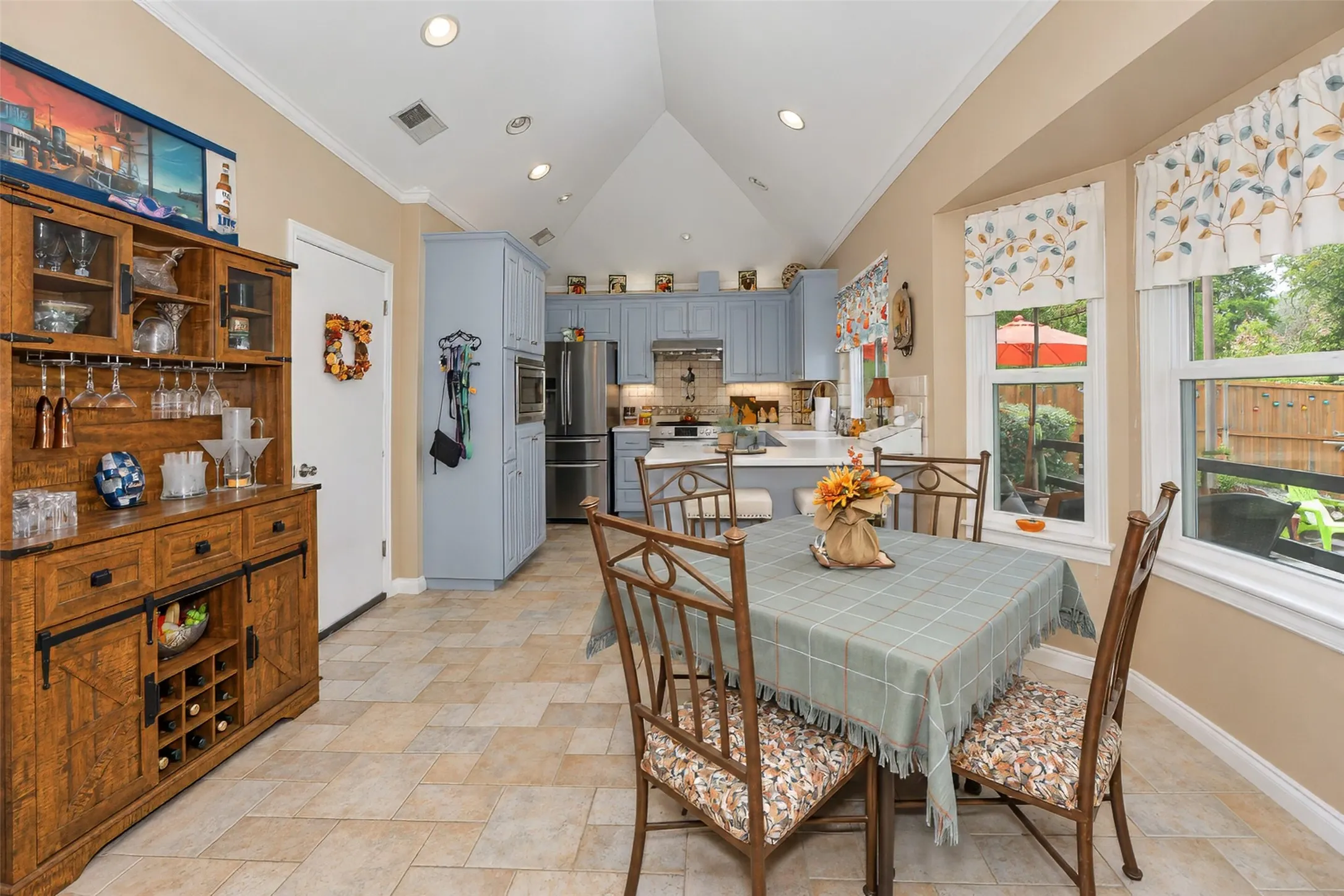 Kitchen with vaulted ceiling, recessed lighting, light blue cabinetry, tiled flooring, and a bay window