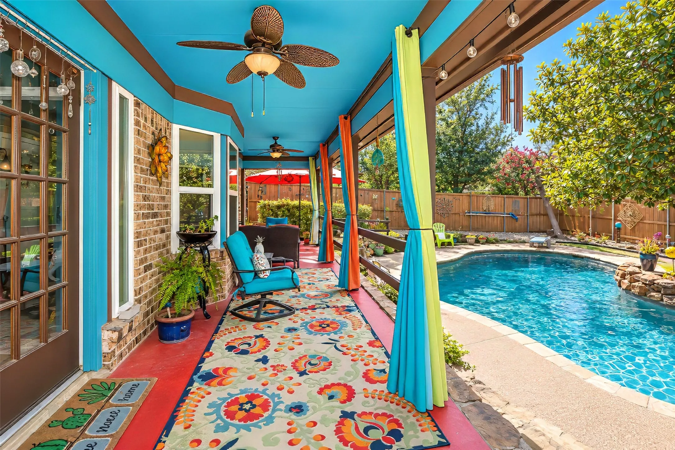 Covered patio with a vibrant ceiling, multiple ceiling fans, and string lighting
