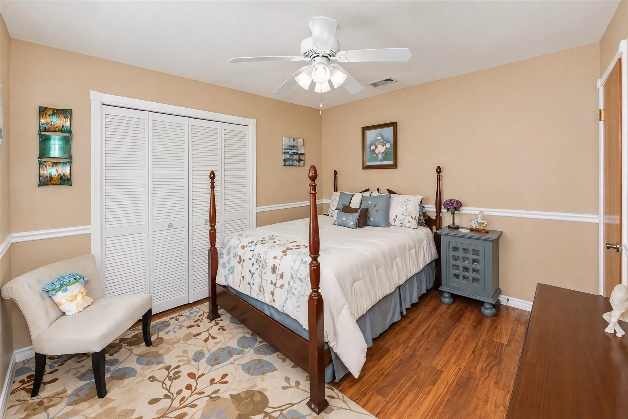 Wood-finish flooring, white louvered bifold closet doors, ceiling fan with integrated lighting, and white crown molding