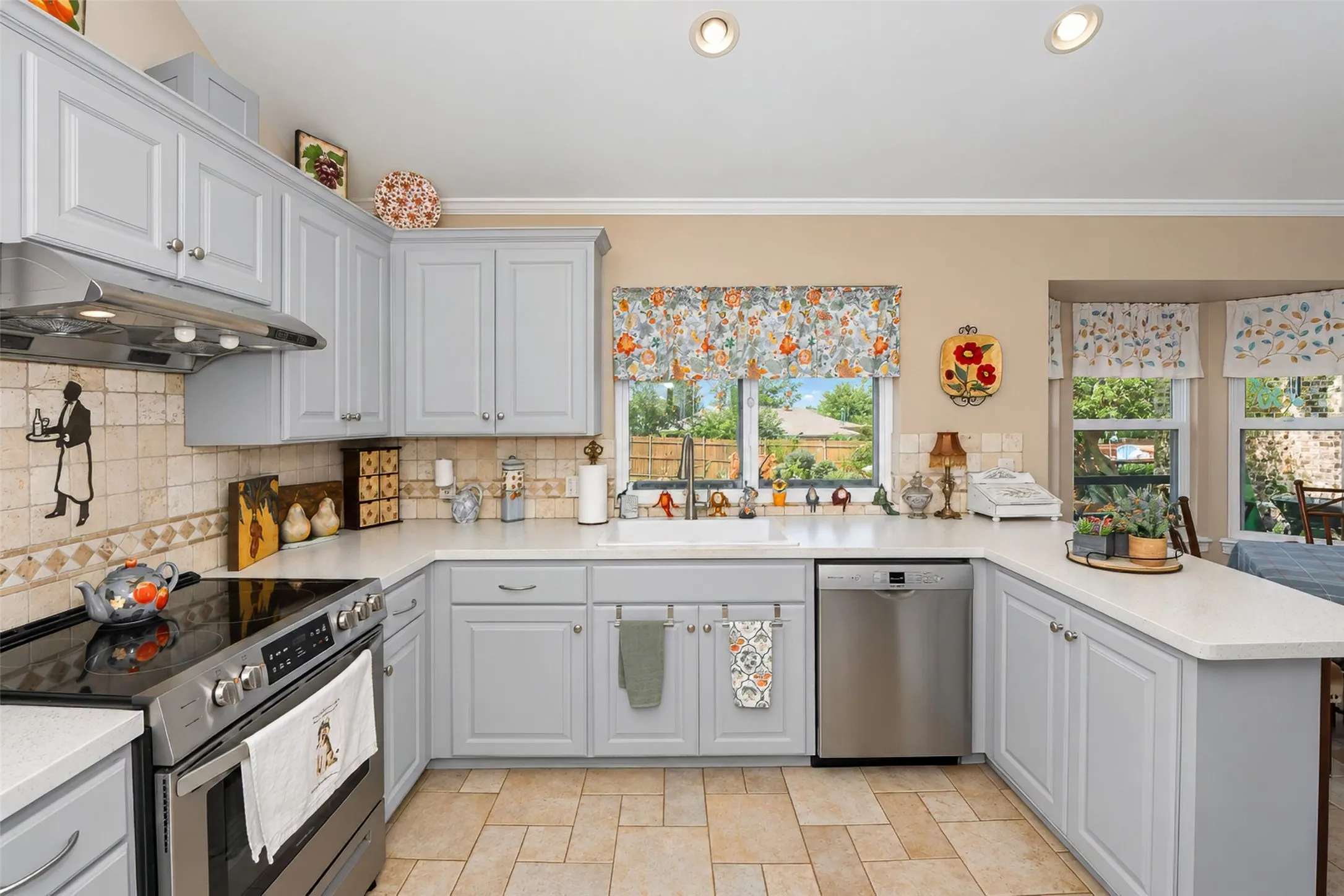 Kitchen featuring light-toned cabinetry, light countertops, stainless steel appliances, a tiled backsplash, and recessed lighting
