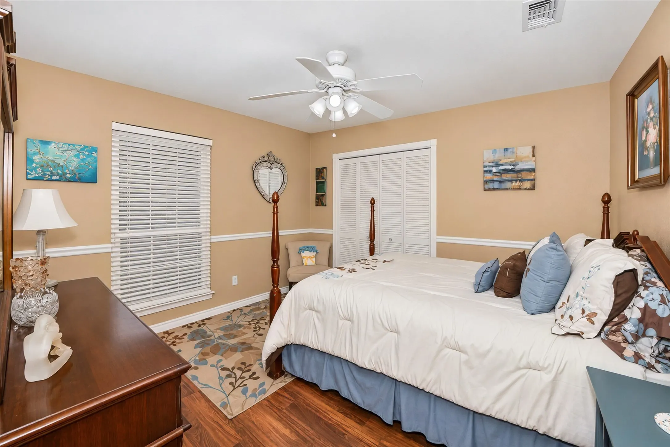 Wood-finish flooring, ceiling fan with integrated lighting, window with horizontal blinds, and bi-fold closet doors