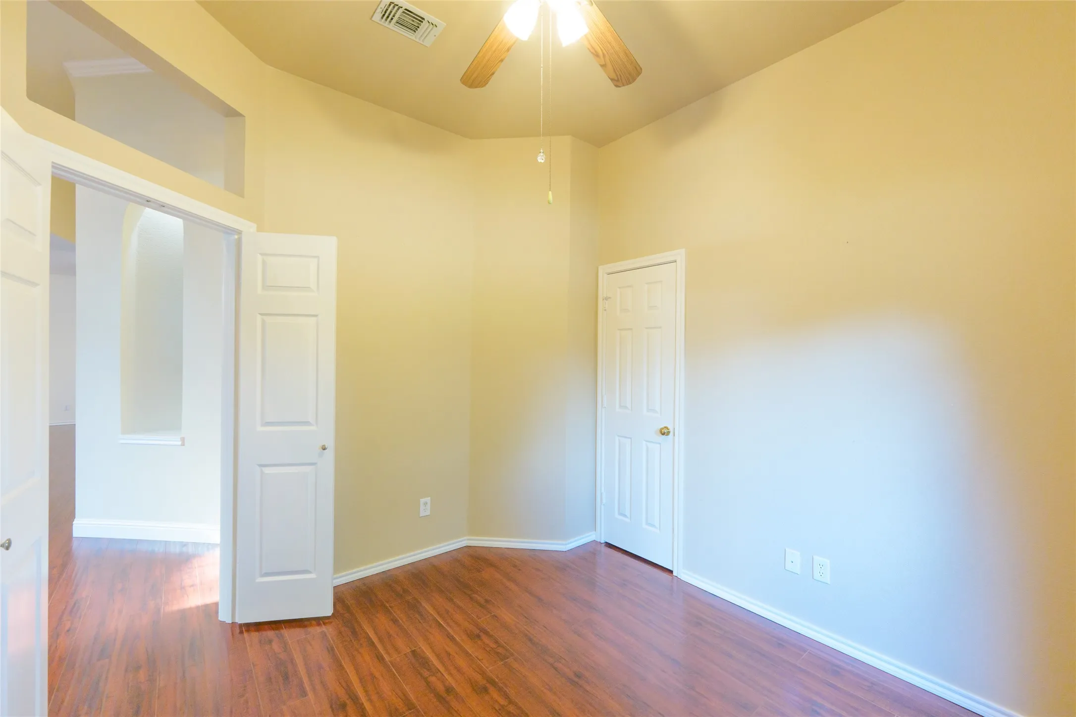 Wood-finish flooring, recessed ceiling, ceiling fan with light fixture, and white interior doors