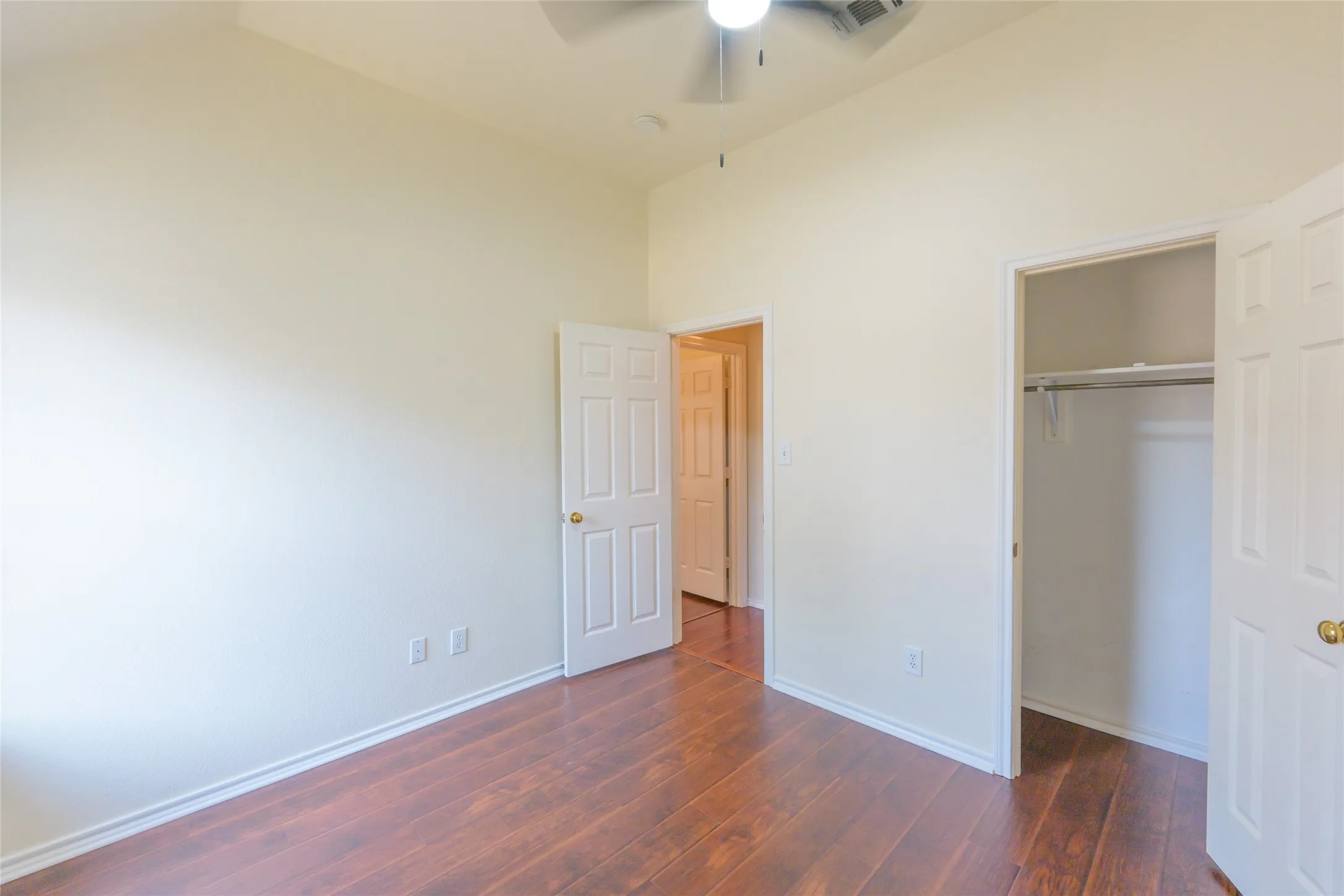 Wood-finish flooring, ceiling fan, and a built-in closet with shelving