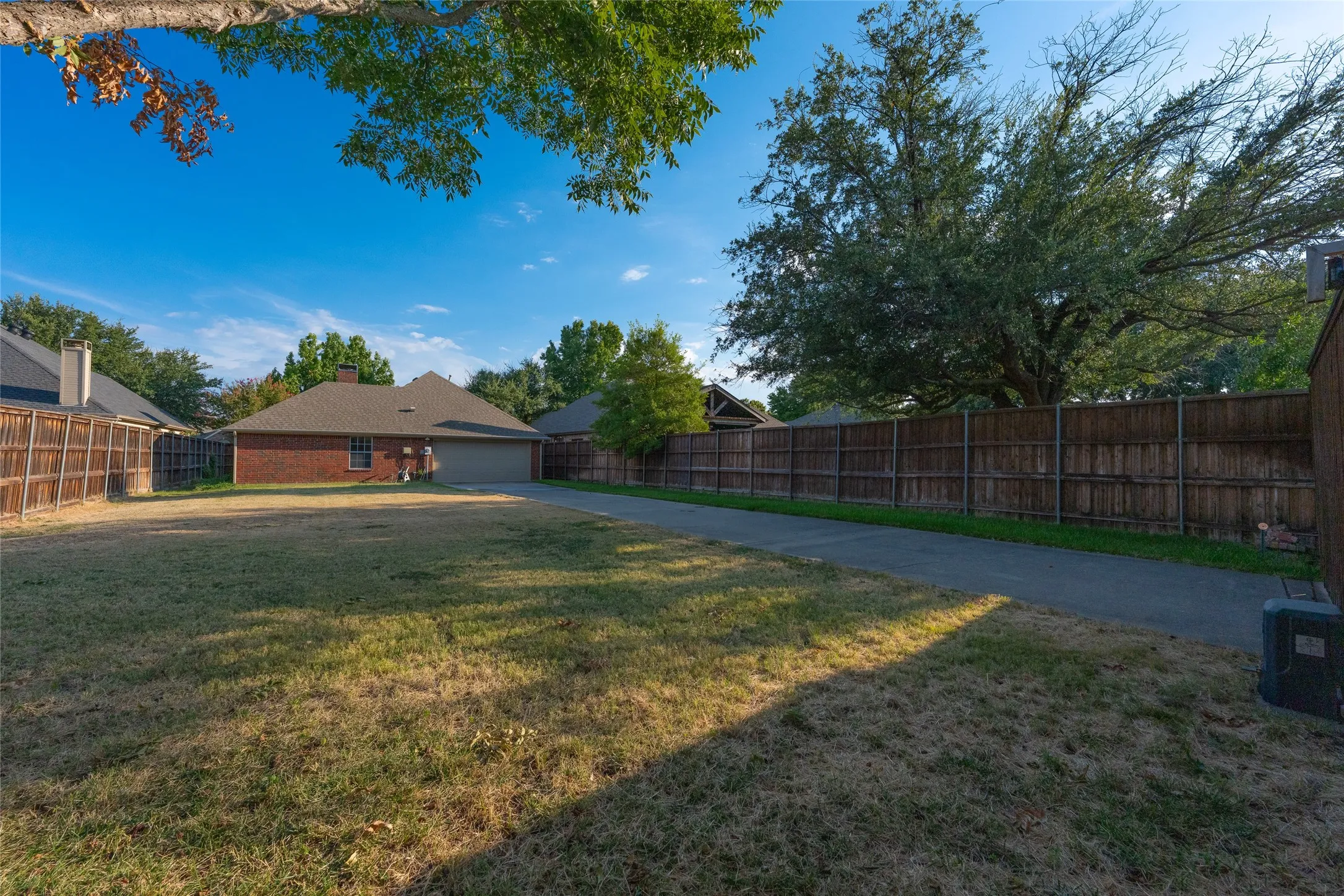 Expansive lawn area with a concrete driveway, brick exterior, and a two-car garage