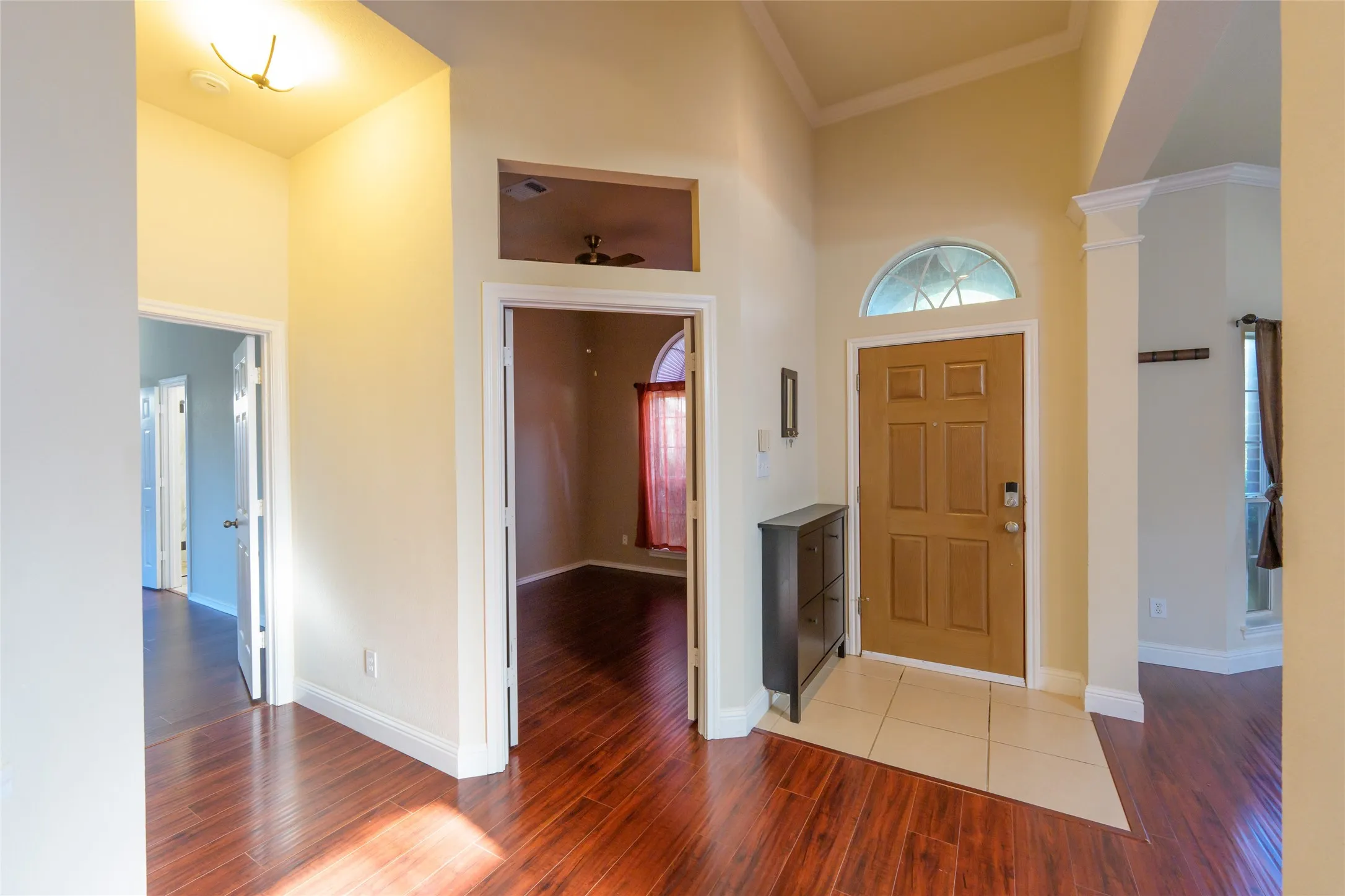 Front entry featuring a wood-panel door with an arched transom, tile flooring, and vaulted ceilings