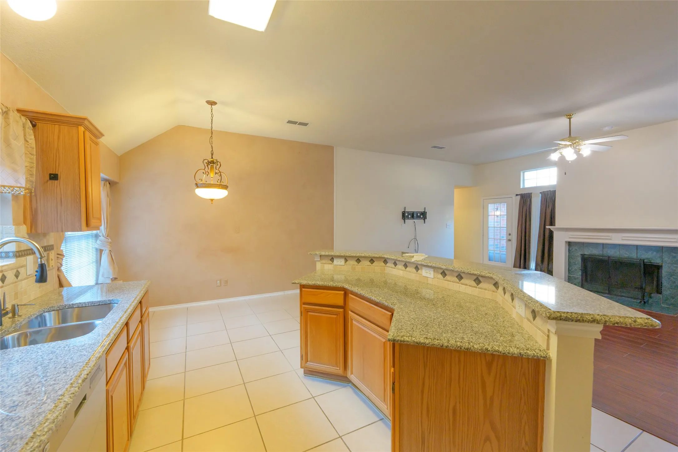 Kitchen featuring granite-style countertops, stainless steel sink, wood cabinetry, and tile flooring