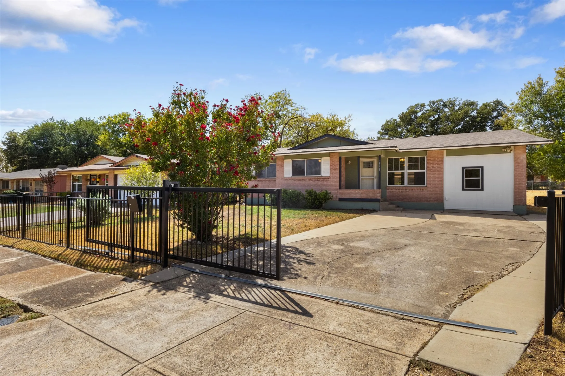 Brick exterior with a partial white facade, a multi-pane window, and a concrete driveway