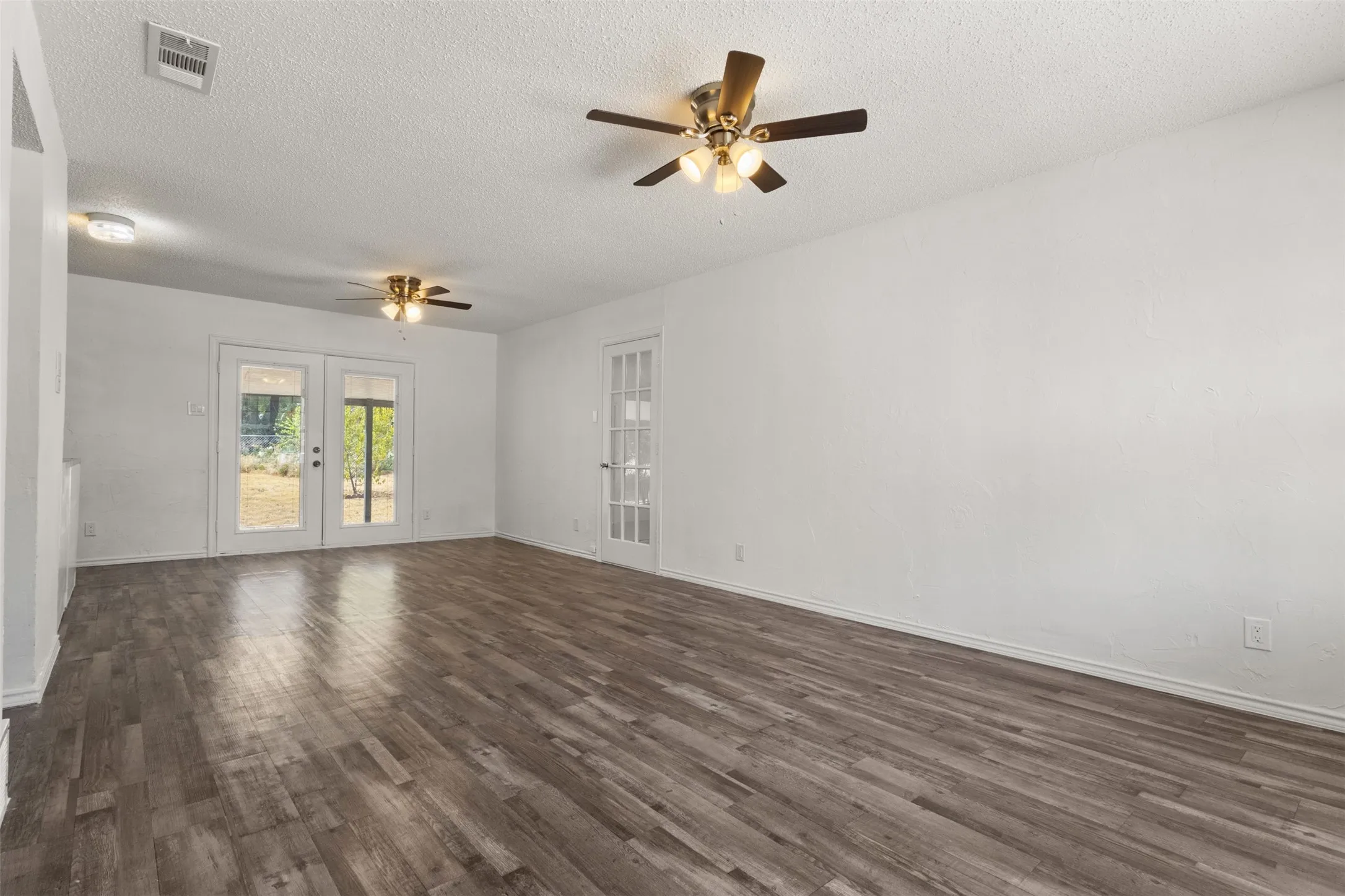 Spacious interior featuring wood-finish flooring, white walls, and dual ceiling fans
