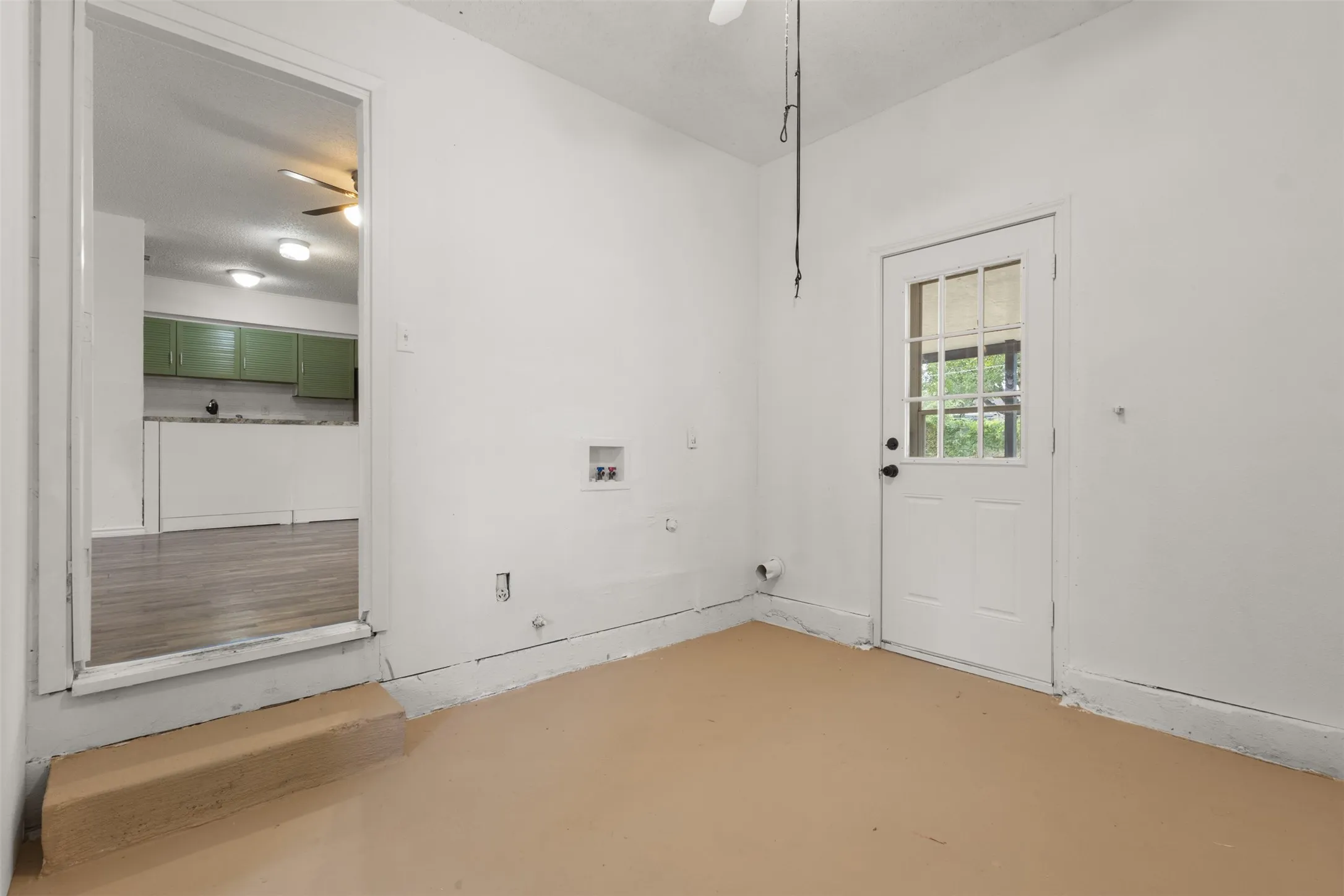 Utility room featuring a paneled door with glass inserts, dedicated laundry hookups, and a neutral-toned floor