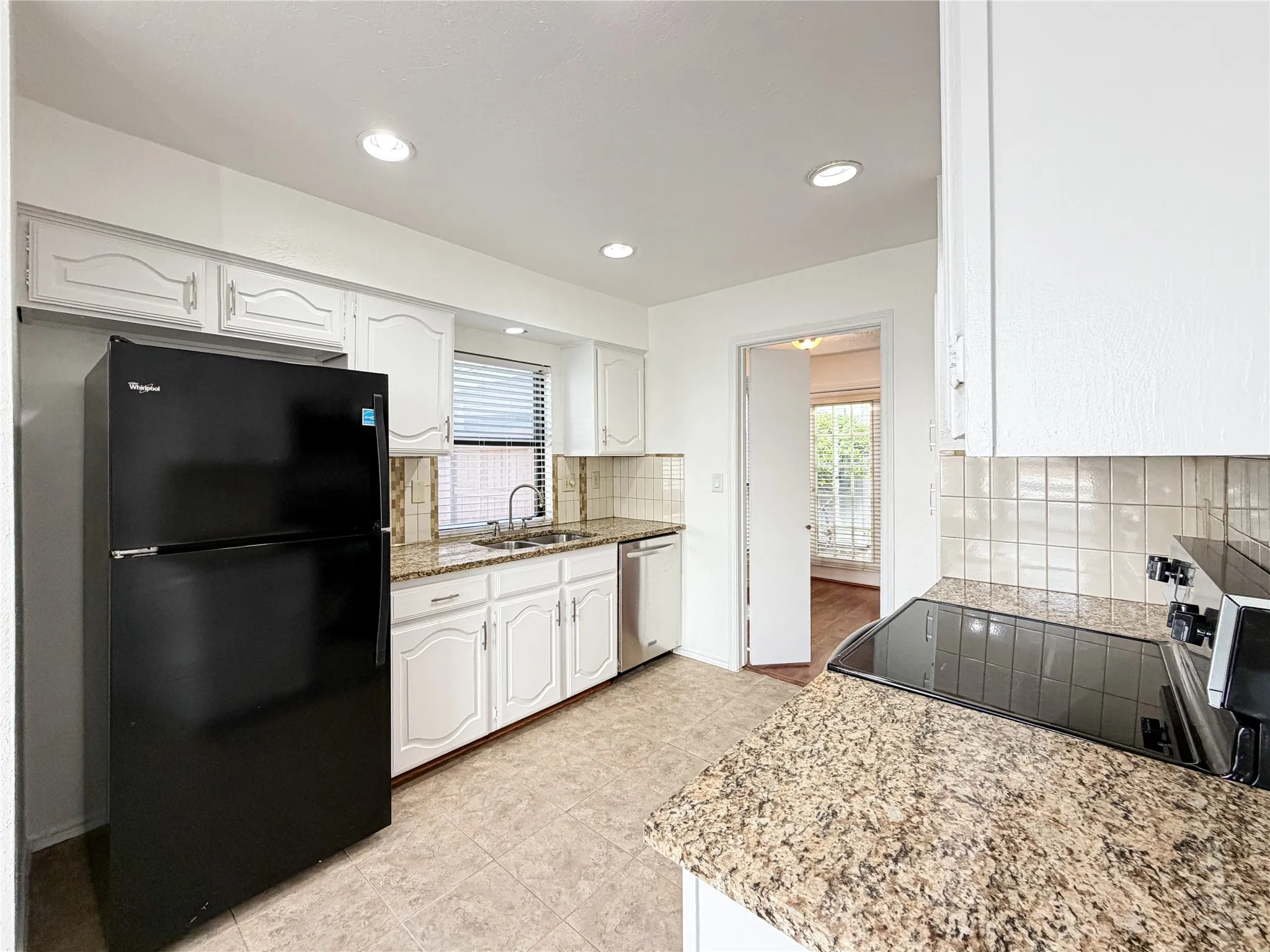 Kitchen featuring granite-style countertops, white cabinetry, a tile backsplash, and recessed lighting