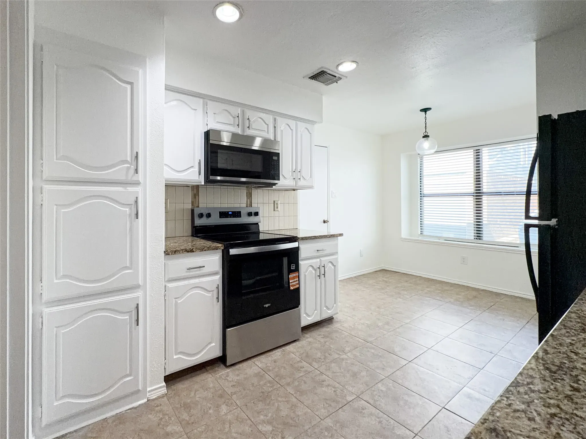 Kitchen featuring white cabinetry, stainless steel microwave, electric range, tiled flooring, and a pendant light fixture