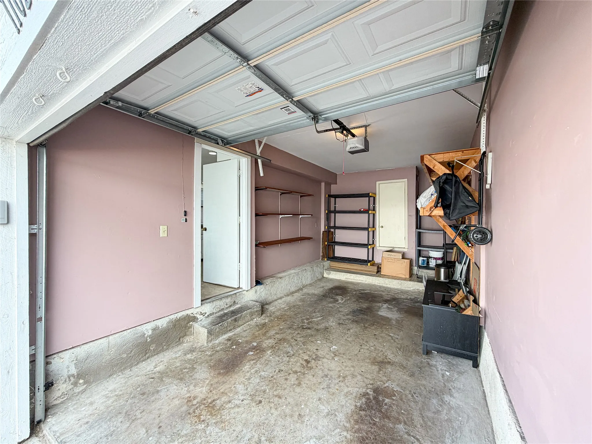 Attached garage with a panel garage door, built-in storage shelving, and an interior access door