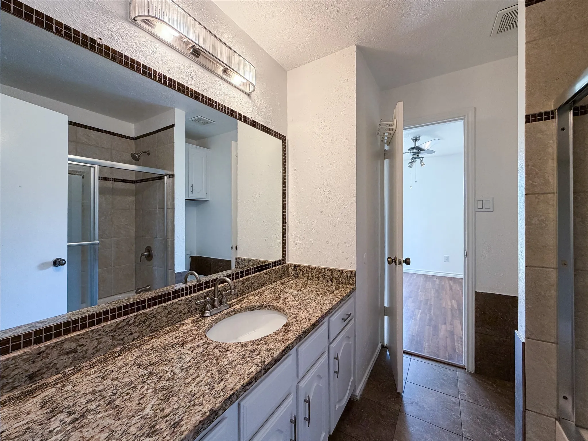 Vanity with integrated sink, granite-style countertop, and white cabinetry