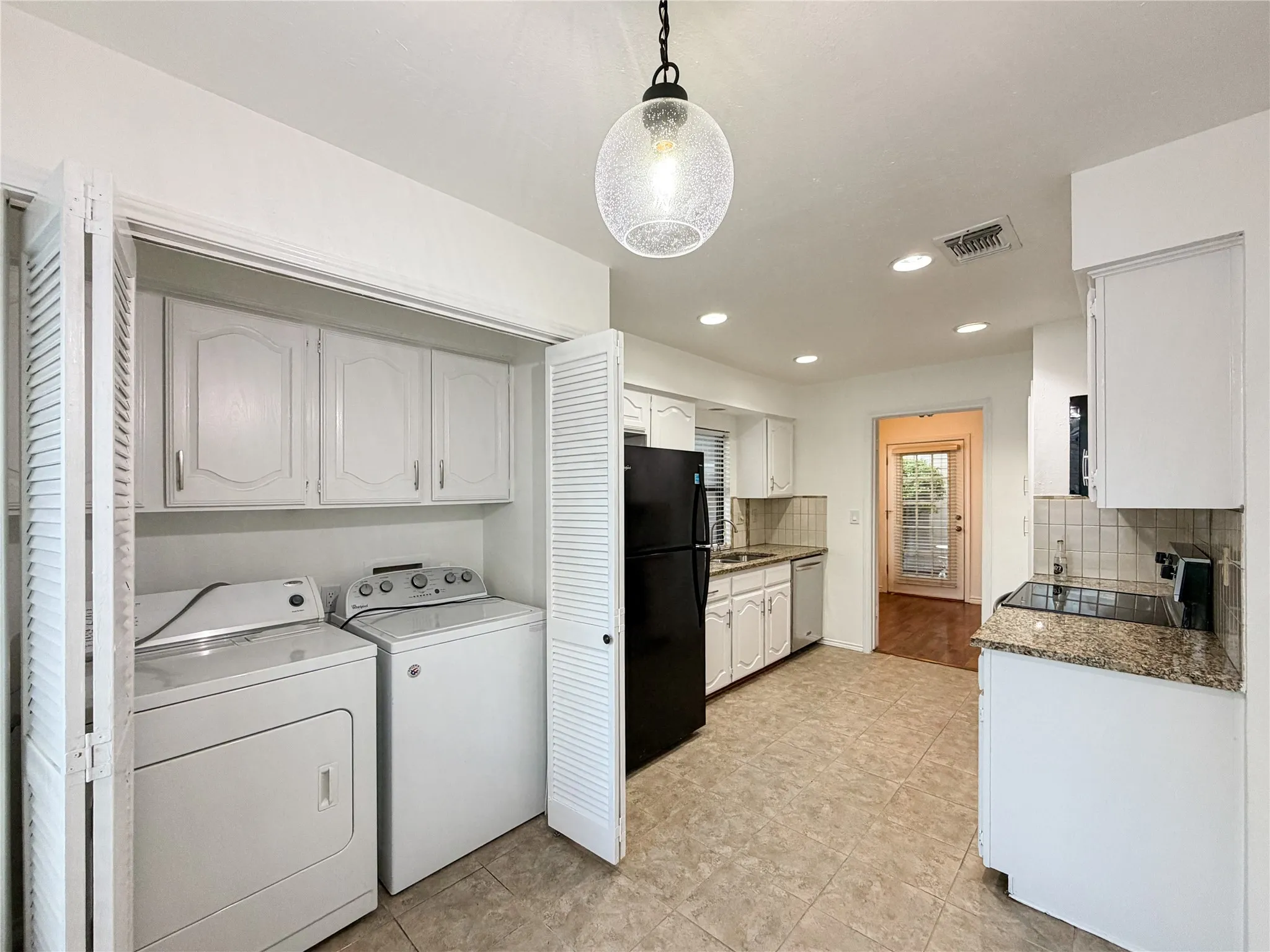Kitchen with white cabinetry, granite-finish countertops, and tile flooring