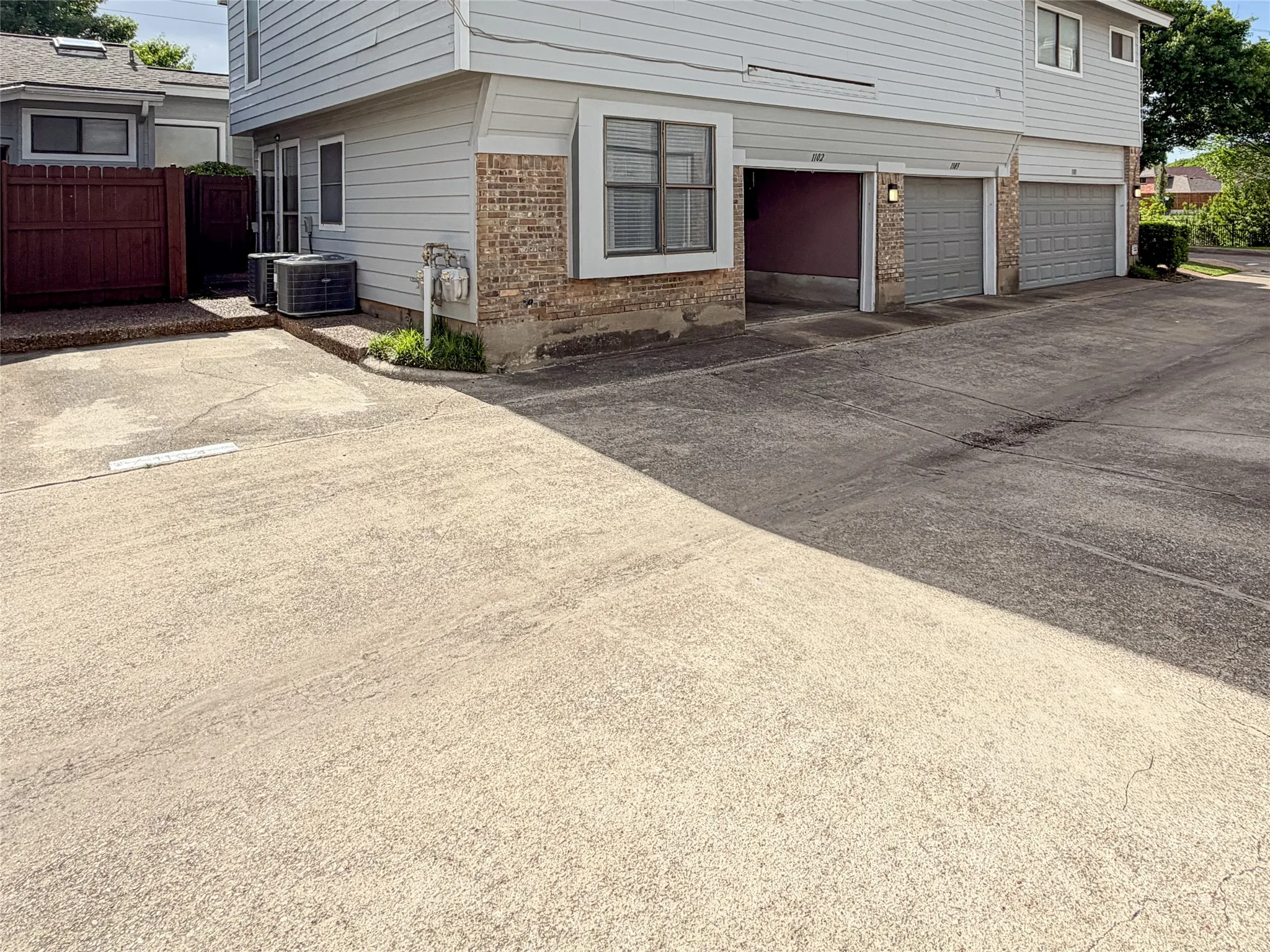 Multi-unit property featuring brick and siding exterior, multiple garage bays, and a concrete driveway