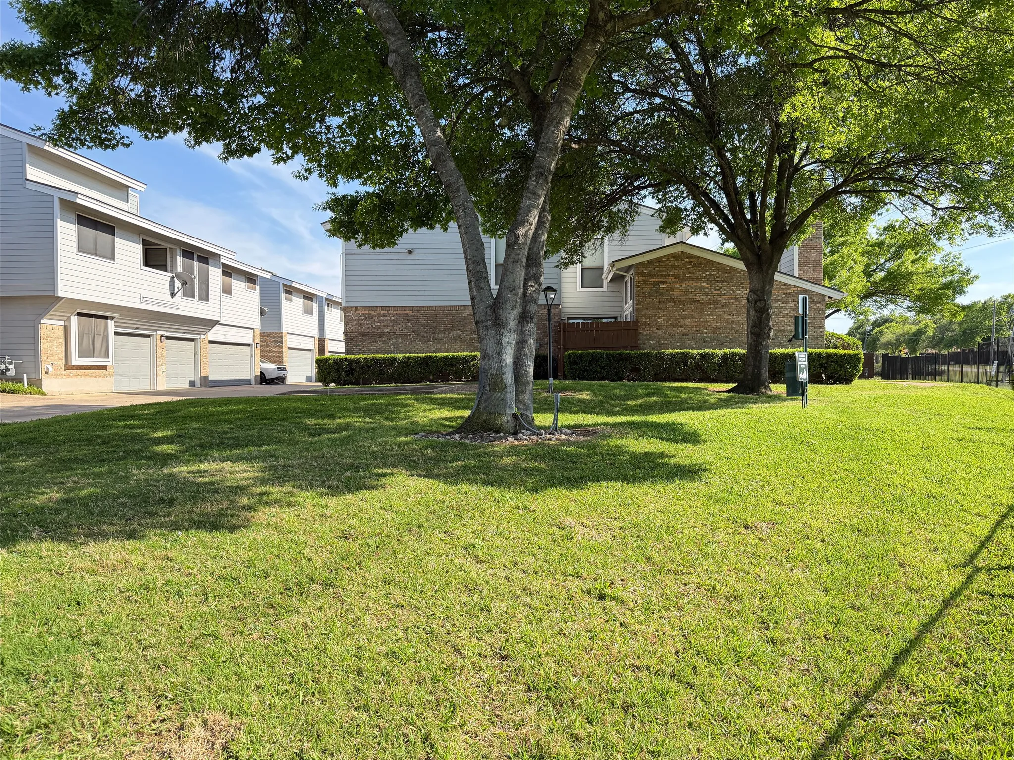 Expansive green lawn with mature trees and a brick and siding exterior