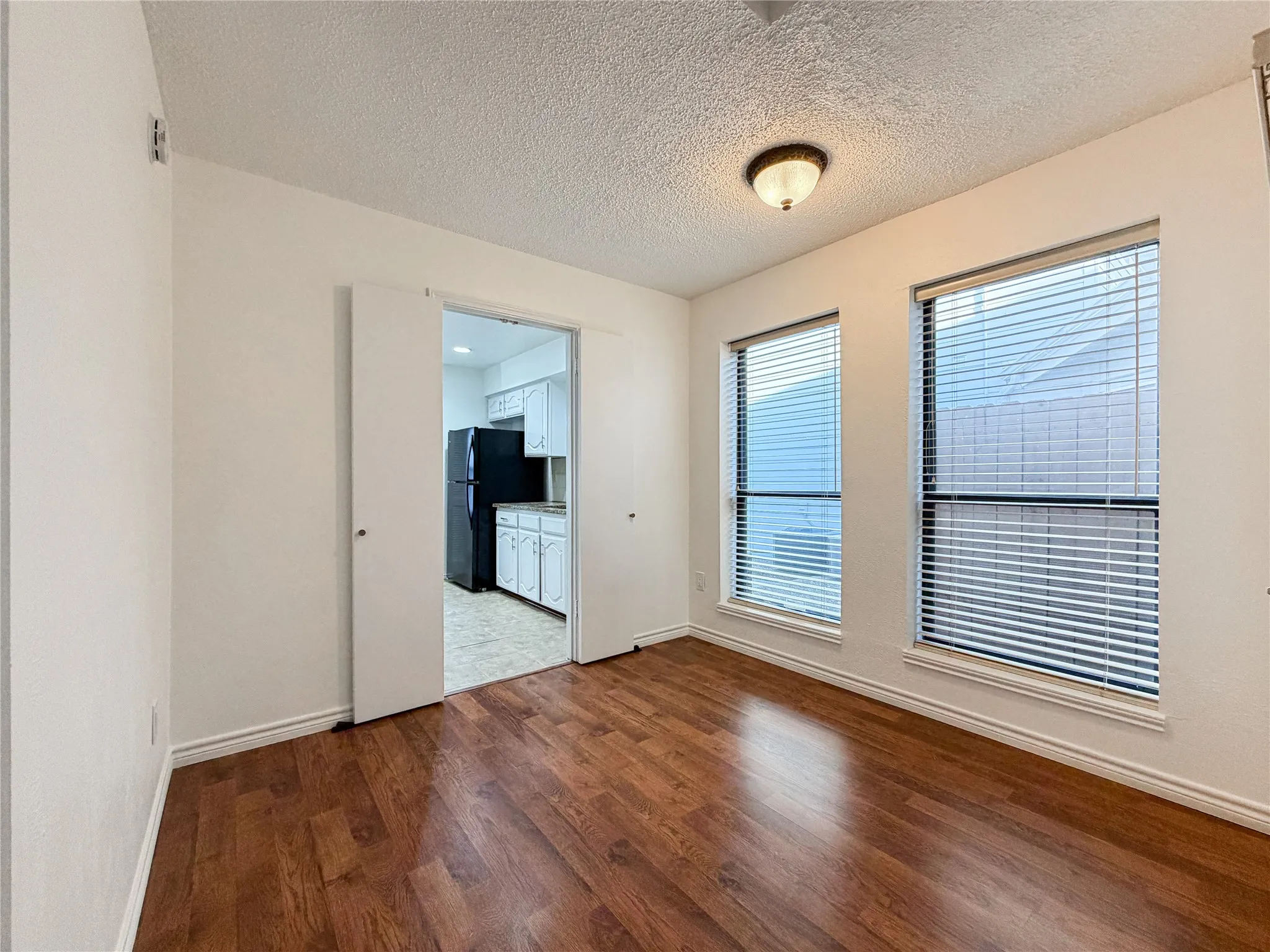Wood-finish flooring throughout, multiple windows with blinds, and a built-in ceiling light fixture