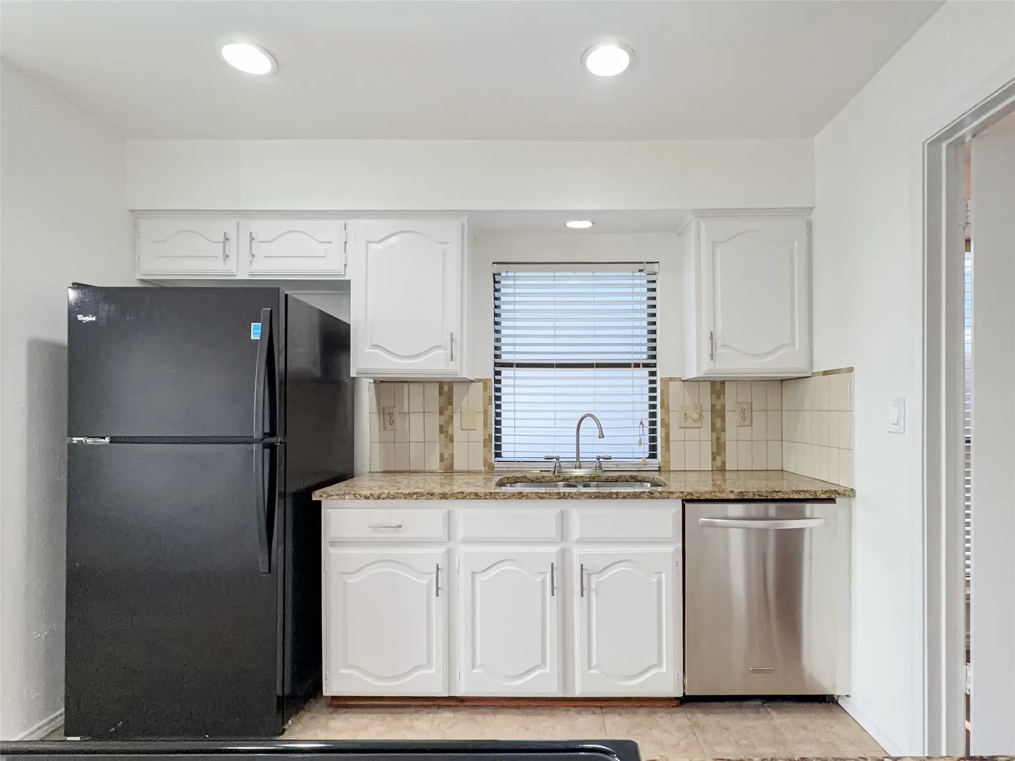 White cabinetry with decorative fronts, speckled countertops, stainless steel dishwasher, and recessed​​‌​​​​‌​​‌‌​‌‌​​​‌‌​‌​‌​‌​​​‌​​ lighting